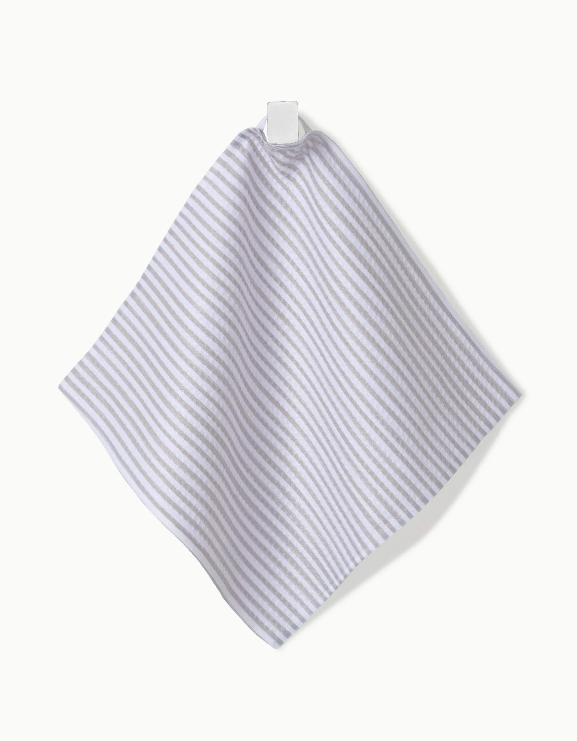 The Kailee Wright À La Carte dishcloth, featuring light gray and white stripes and made from Geoweave fabric, hangs from a white fabric loop against a crisp white background.