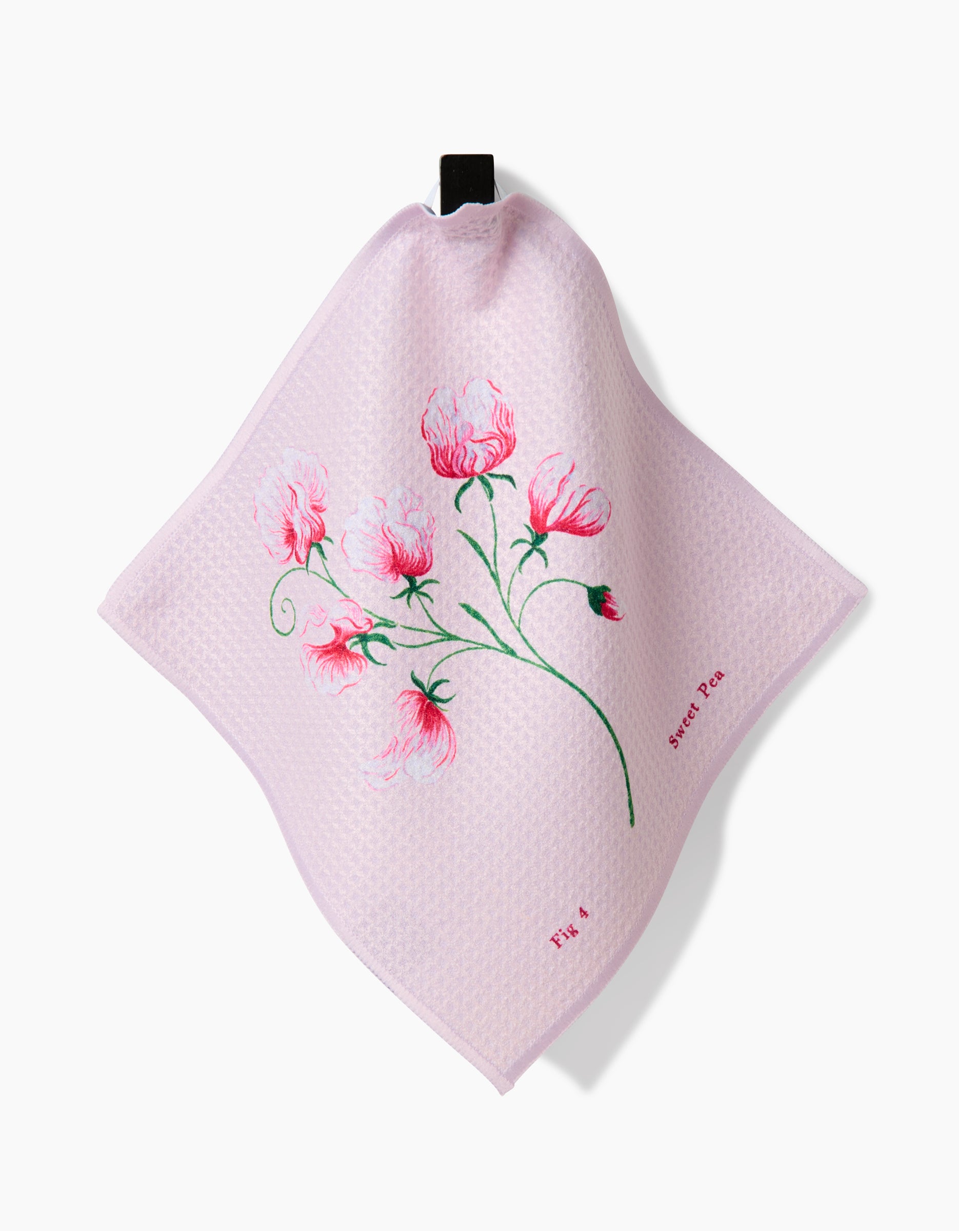 The April Sweet Pea dishcloth by Linda Fox is a pale pink Geoweave fabric with a textured finish, featuring sweet pea flowers and green stems along with Sweet Pea and FIG. 4 printed near the floral illustration.