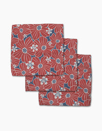 The Ashley Celena Botanical Blush set features three folded cloth napkins with bold red and white floral patterns on a dark blue background, neatly stacked for display against a crisp white backdrop.