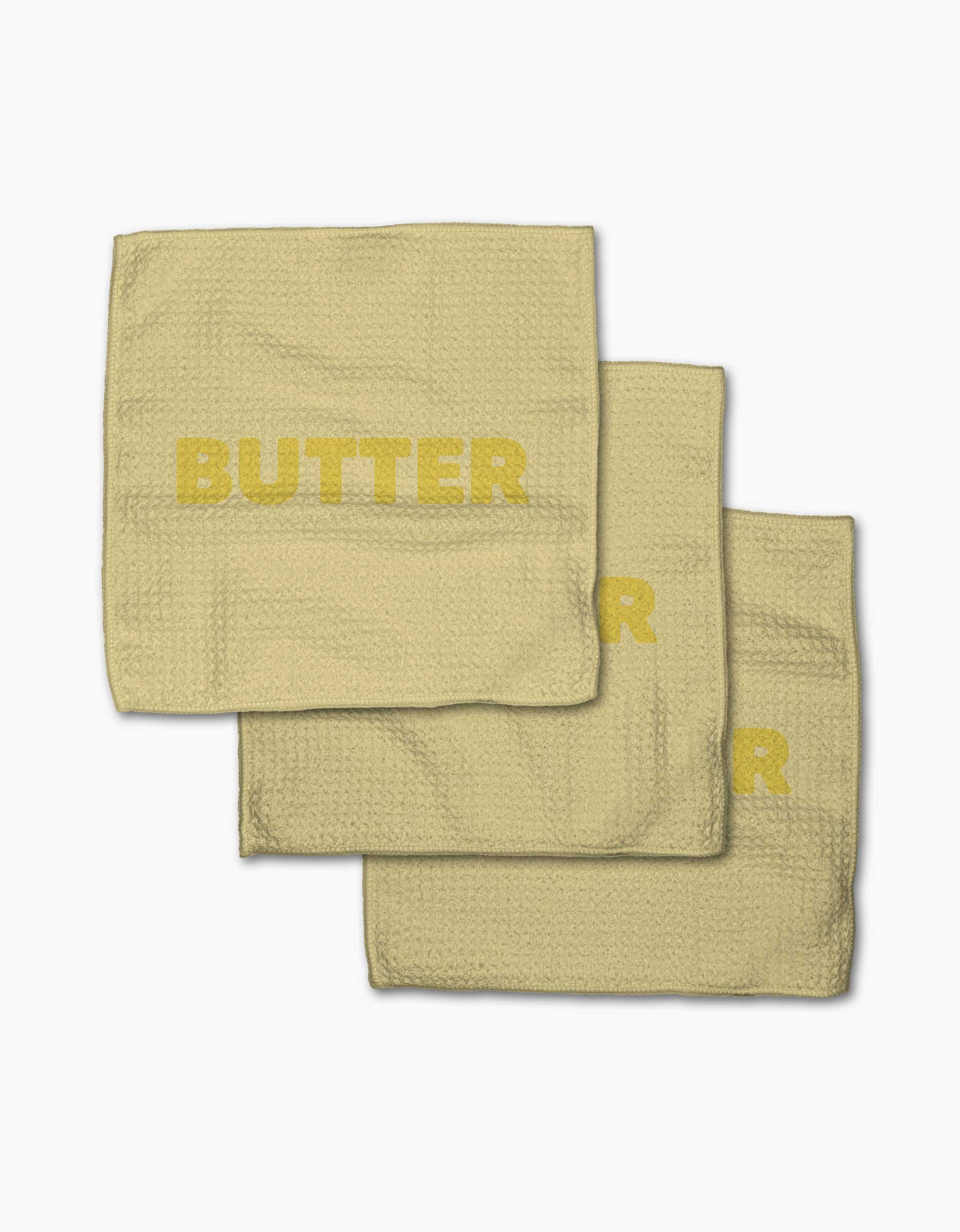 Three yellow GEOMETRY Butter napkins, made from Geoweave fabric and printed with BUTTER in bold capitals, are shown slightly overlapping on a plain white background.