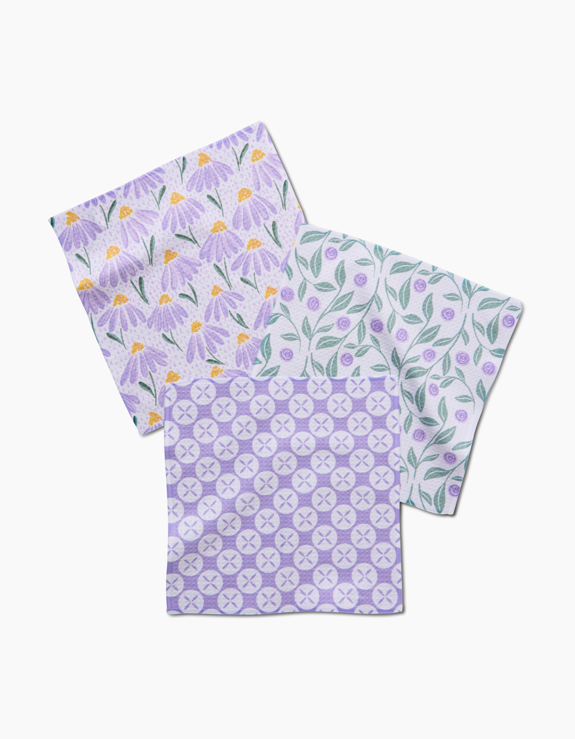 Hufton Studio’s Button Vines and Daisies set includes three recycled cloth napkins: purple flowers with yellow centers, green leaves on white, and a purple geometric pattern.