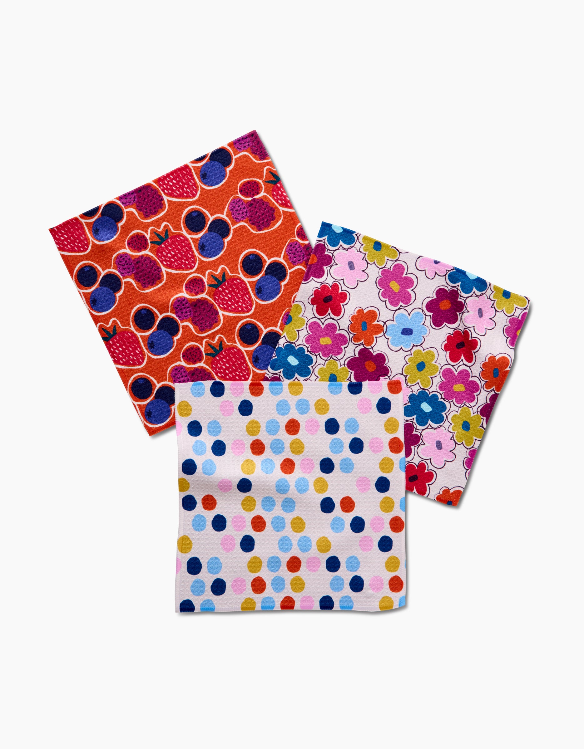 The Lizzie Clark Carnival Fling set includes three vibrant Geoweave dishcloths—featuring abstract shapes, floral designs, and polka dots—all crafted from recycled materials.