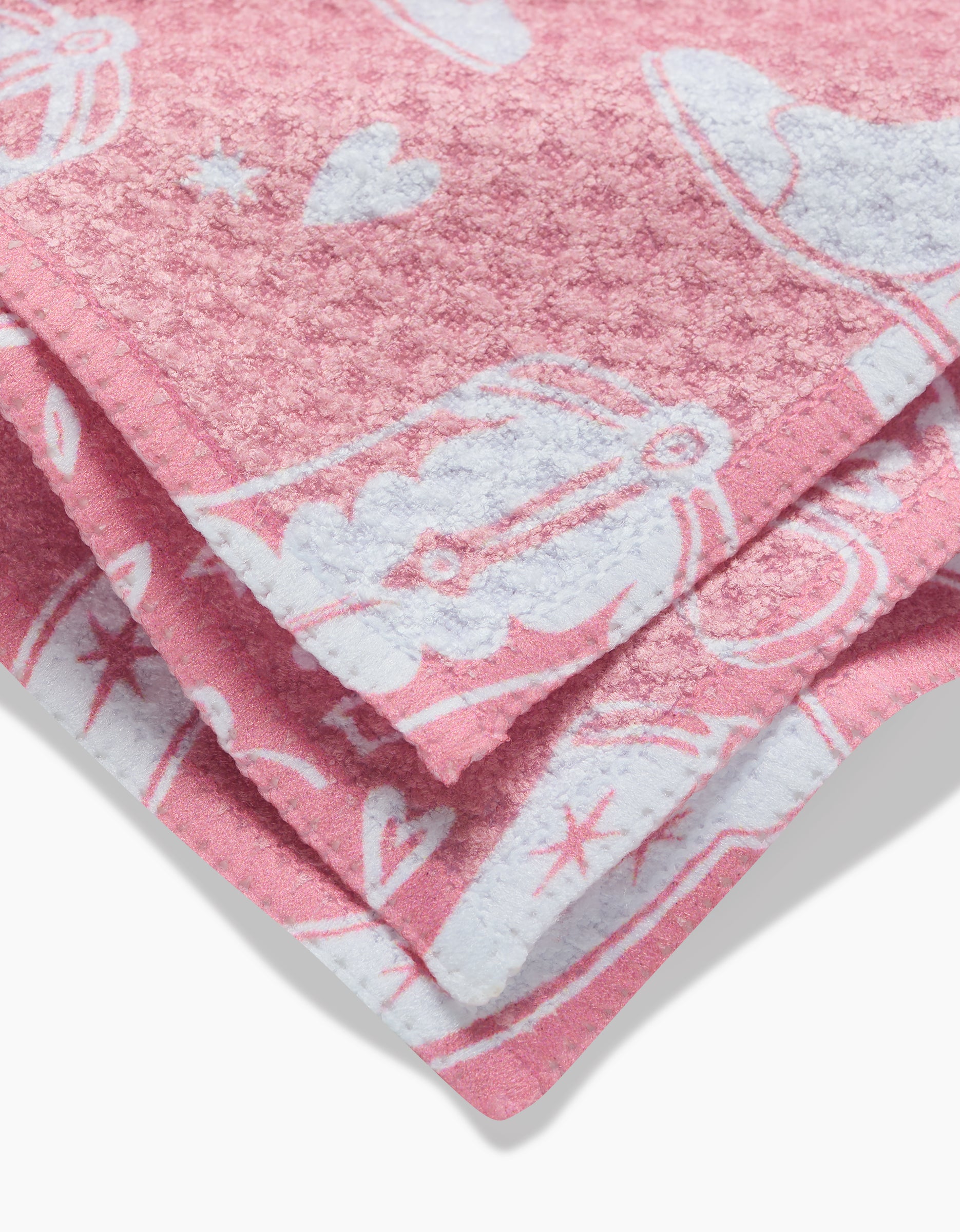 A close-up of the folded Chic Lucky Boots pink dishcloth, featuring white cowboy hats, boots, hearts, and stars on soft Geoweave fabric.