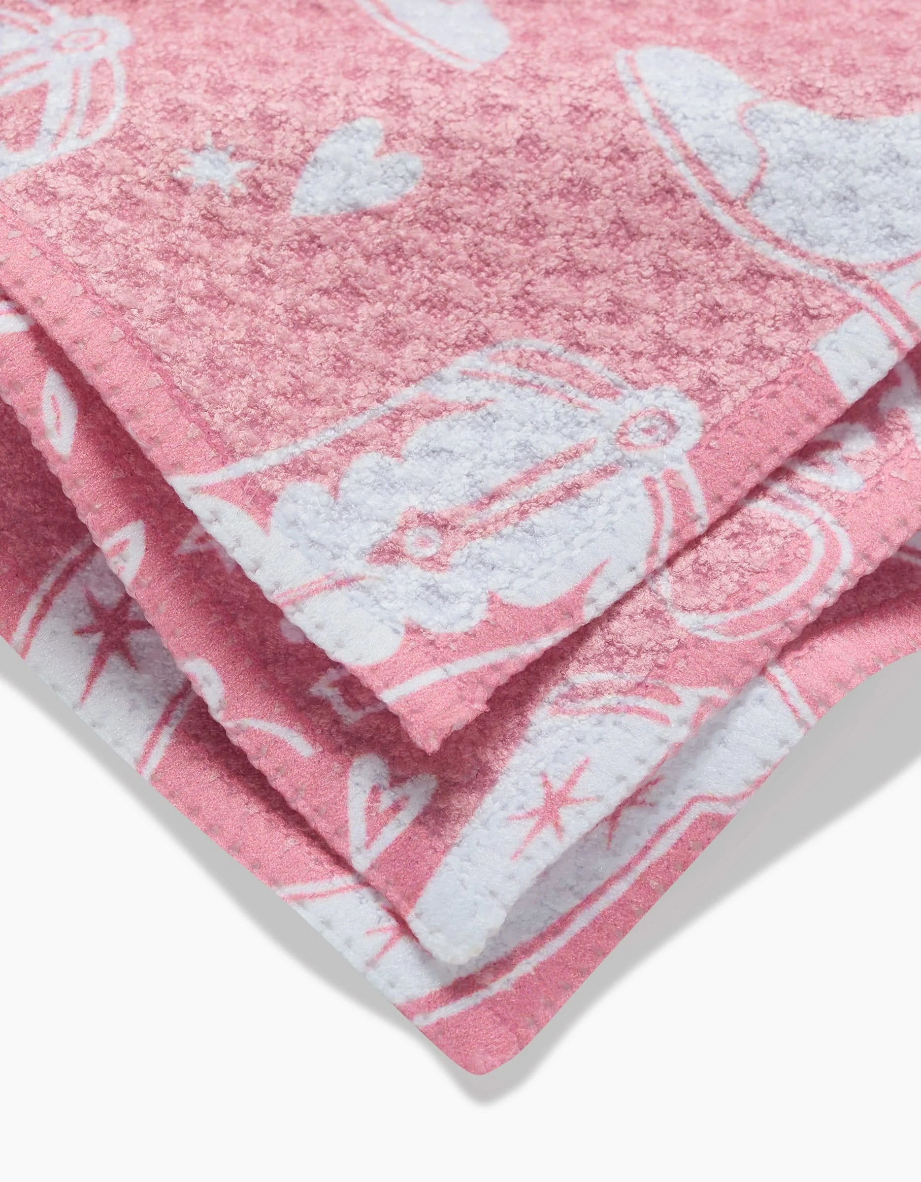 A close-up of the folded Chic Lucky Boots pink dishcloth, featuring white cowboy hats, boots, hearts, and stars on soft Geoweave fabric.