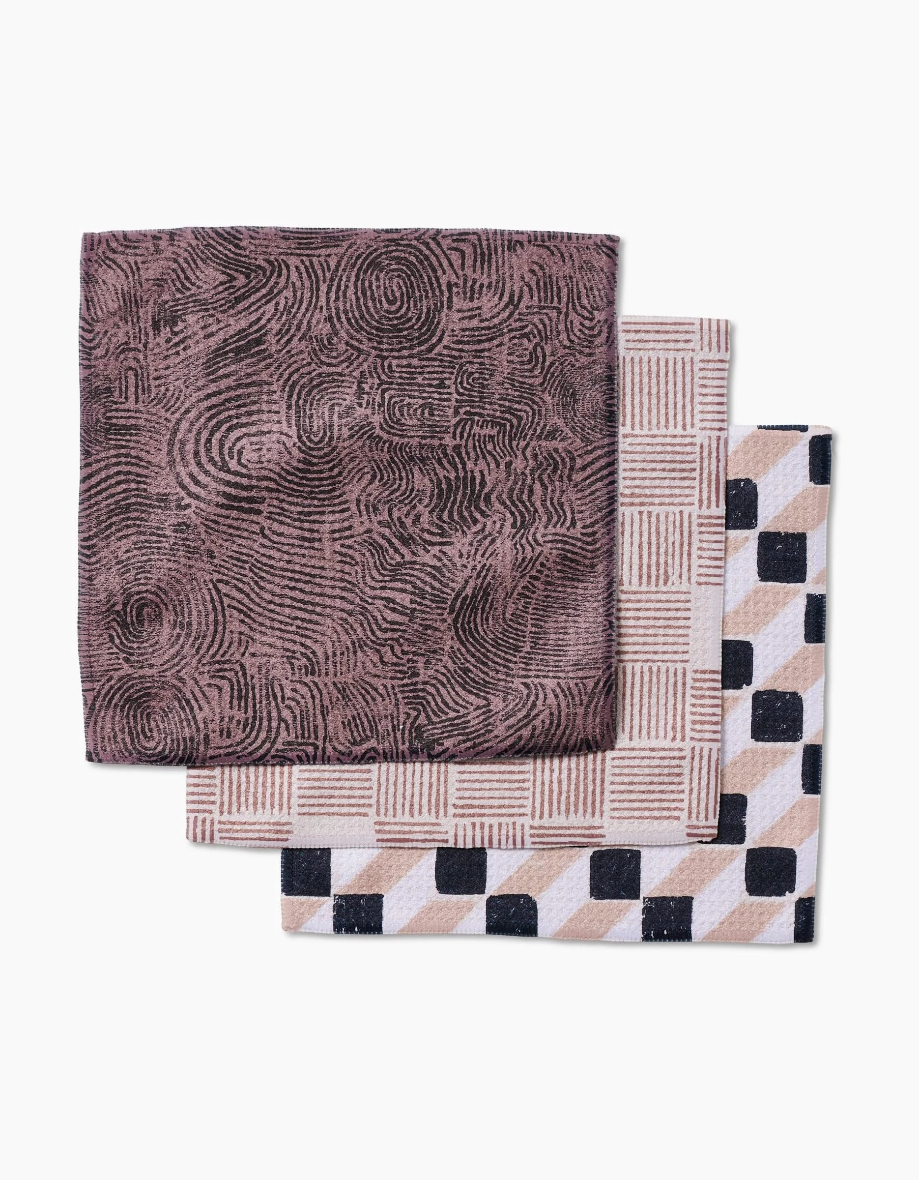 Three folded Studio Jeannot Chiseled Geoweave washcloths: the top has a brown and black swirl, the middle shows a beige and white grid, and the bottom displays a black, beige, and white checkered pattern.
