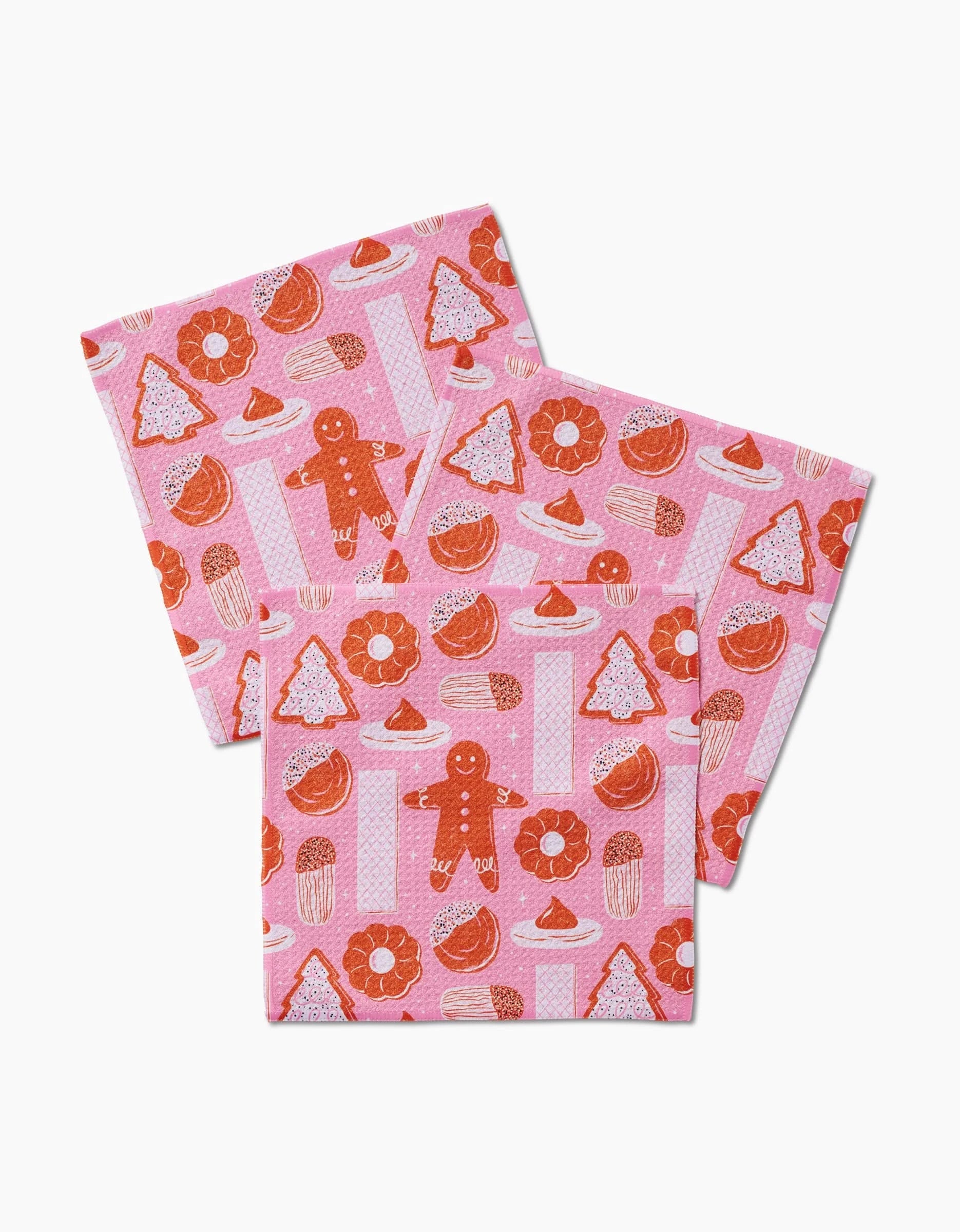 Set of three pink Christmas Cookies dishcloths by Megan Roy, made from recycled materials and featuring red gingerbread men, Christmas trees, and assorted festive treats on a light pink polka dot background.
