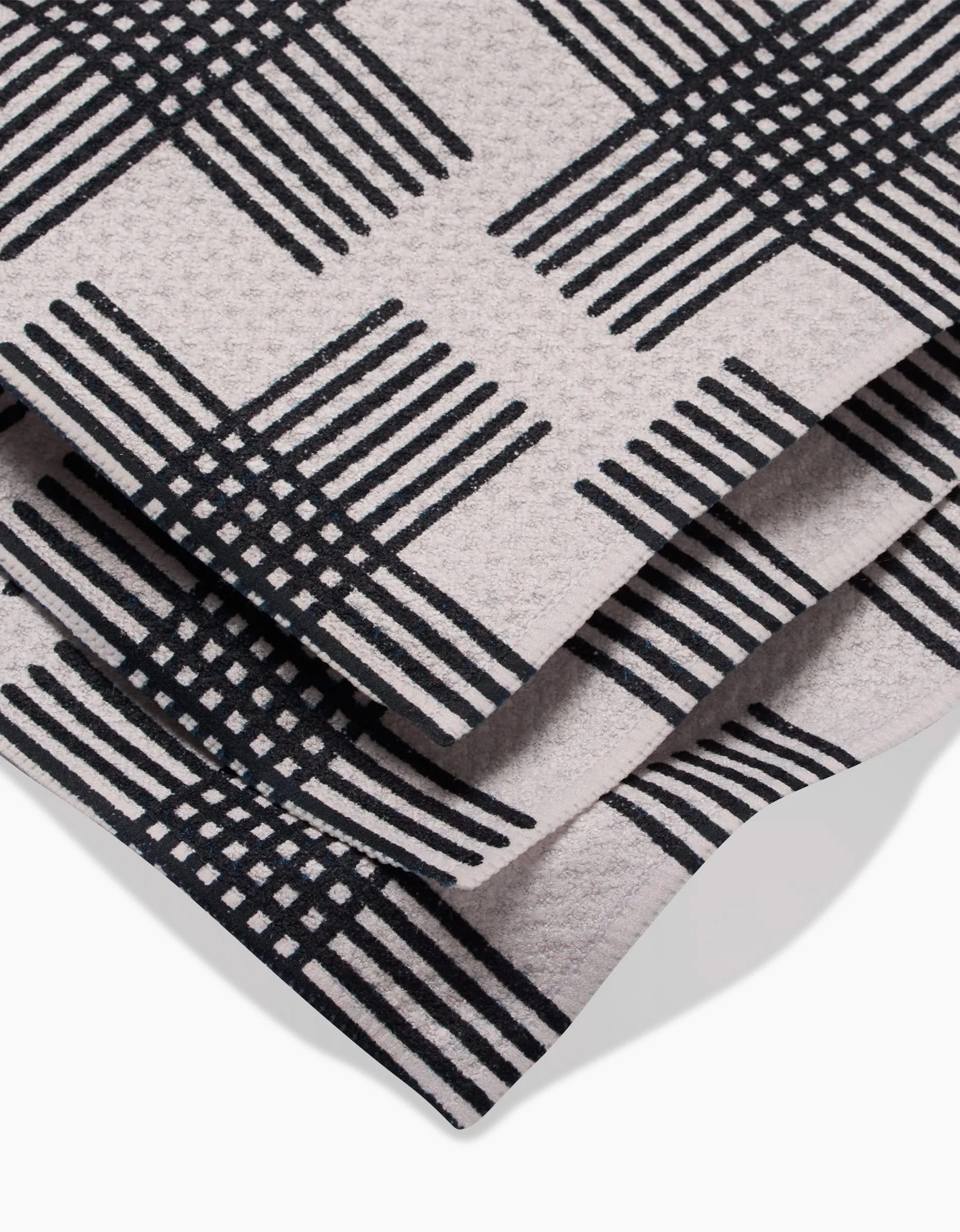 A close-up of Cross Hatch by Rosa Kichline shows folded Geoweave fabric with a beige background and bold black intersecting lines, ideal for super-absorbent dishtowels or a stylish Dishcloth Set.