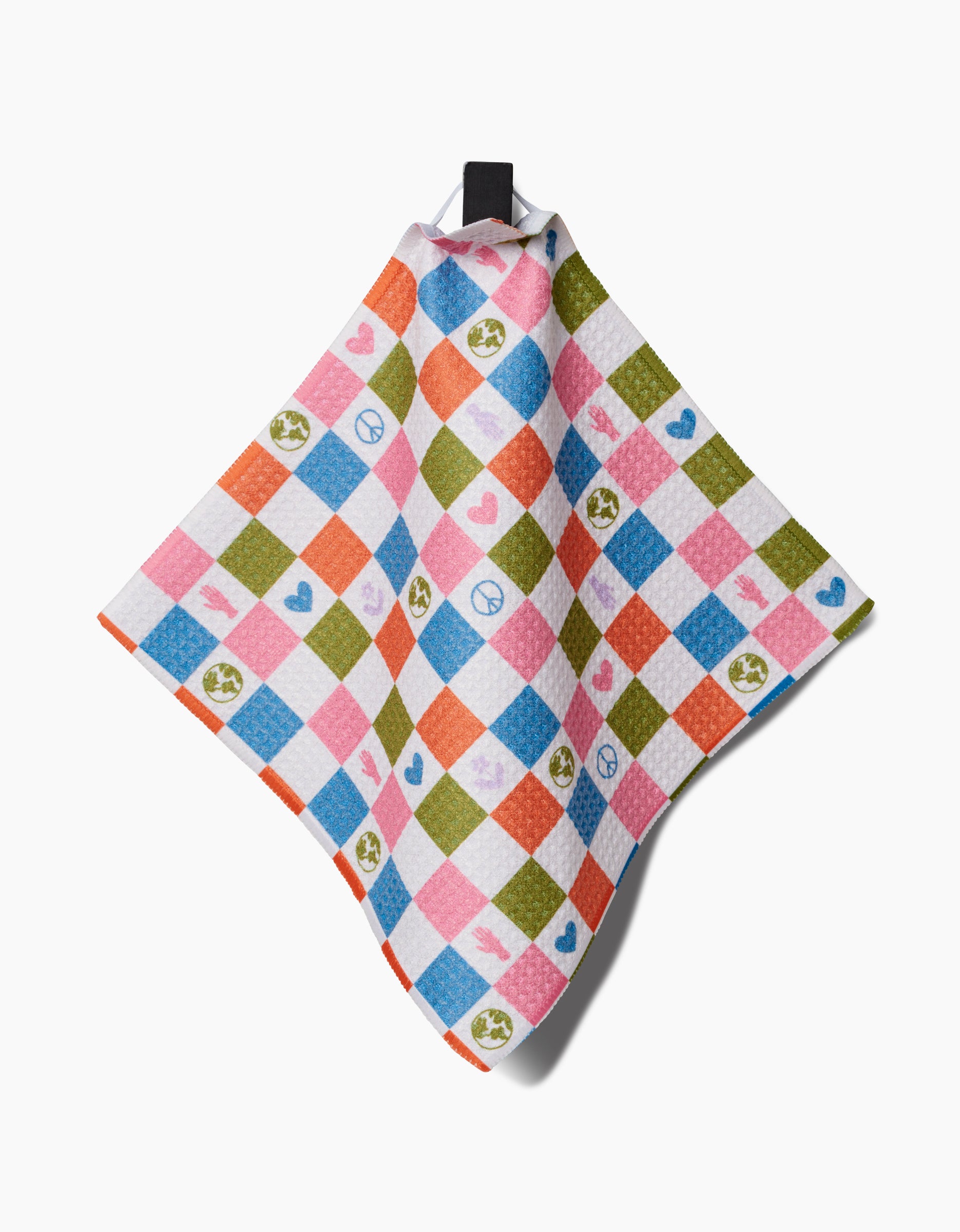 The Kayla Ann Earth Day Checkers dishcloth features a checkered Geoweave design in blue, pink, orange, and green with peace signs, hearts, and Earth symbols. It hangs by a black loop against a white background.