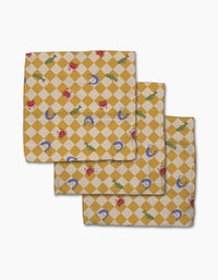 The Geometry El Mar Abierto set includes three folded yellow and white checkered dishcloths with diamond patterns, each featuring red crabs, green alligators, and blue shells—a super-absorbent and charming choice.