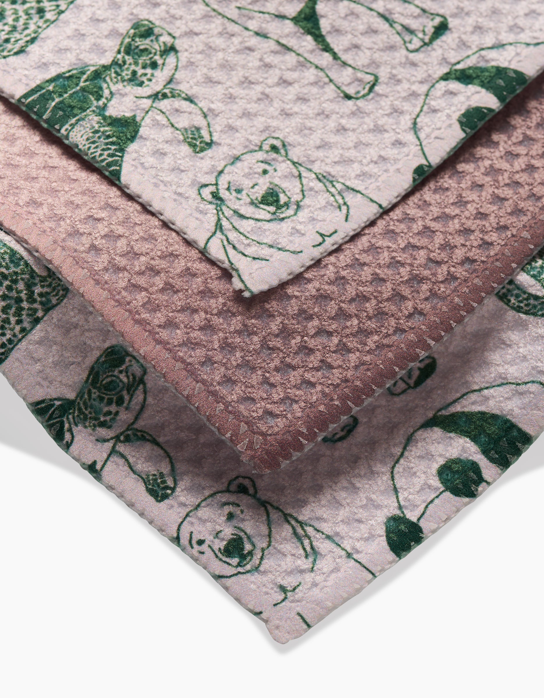 Three Endangered dishcloths by GEOMETRY, each featuring dark green animal line drawings—a turtle, polar bear, and panda—on mauve-pink backgrounds; made from recycled materials.