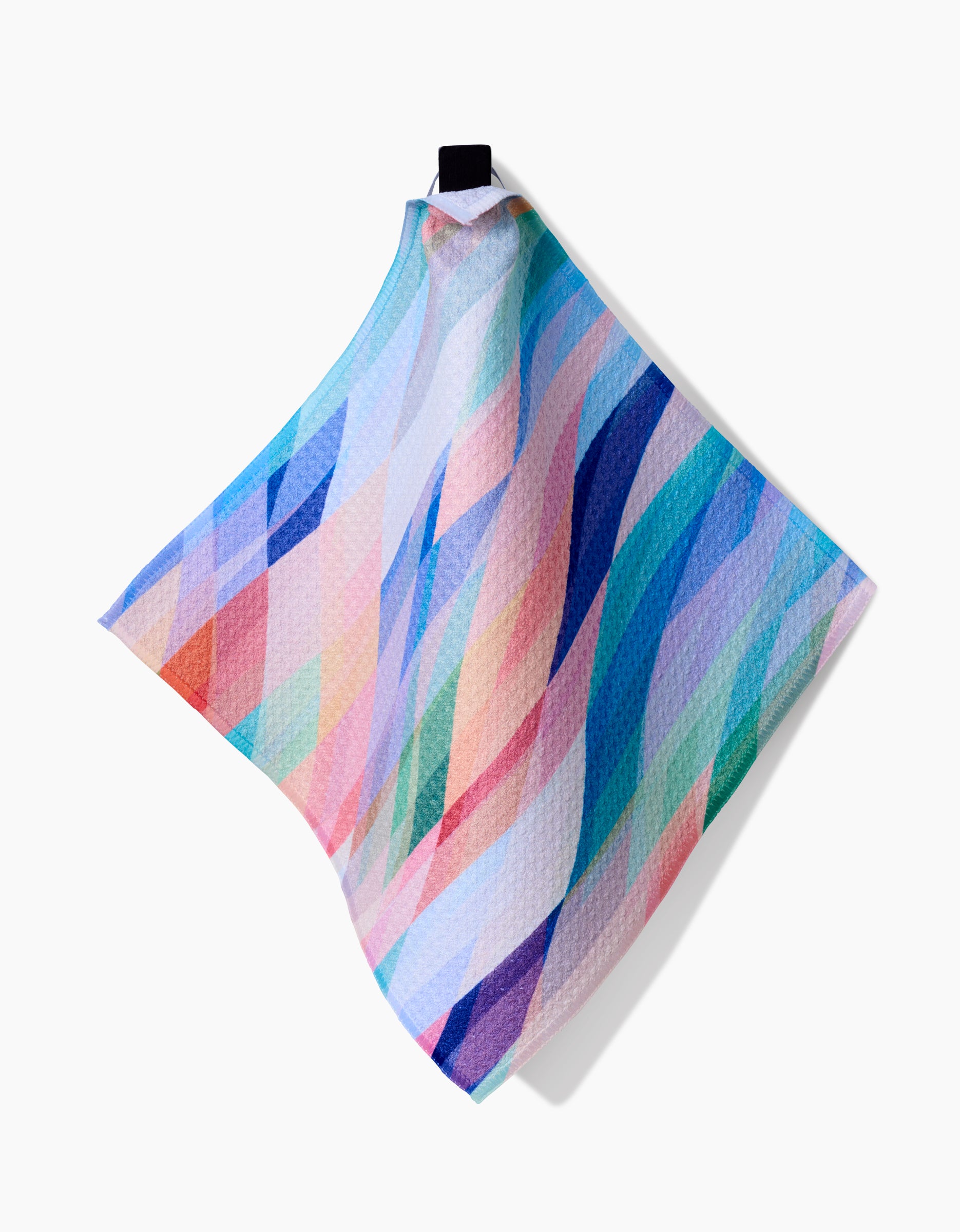 Eventide by Rachel Parker is a textured dishcloth made from Geoweave fabric, featuring a colorful abstract pattern of overlapping curved lines in blue, pink, purple, and green, with a black hanging loop against a white background.