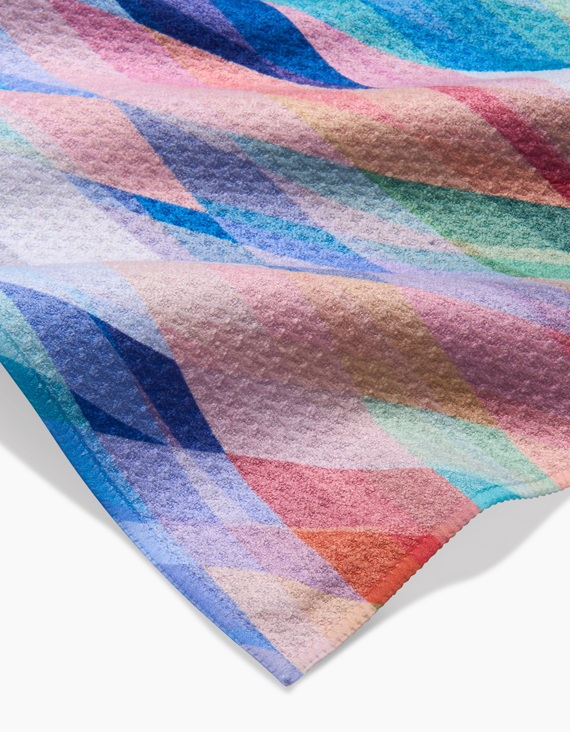 A close-up of Rachel Parker’s Eventide dishcloth shows its textured Geoweave fabric and colorful abstract geometric pattern with overlapping blue, pink, red, green, and purple shapes. The edge of the dishcloth appears in the corner.