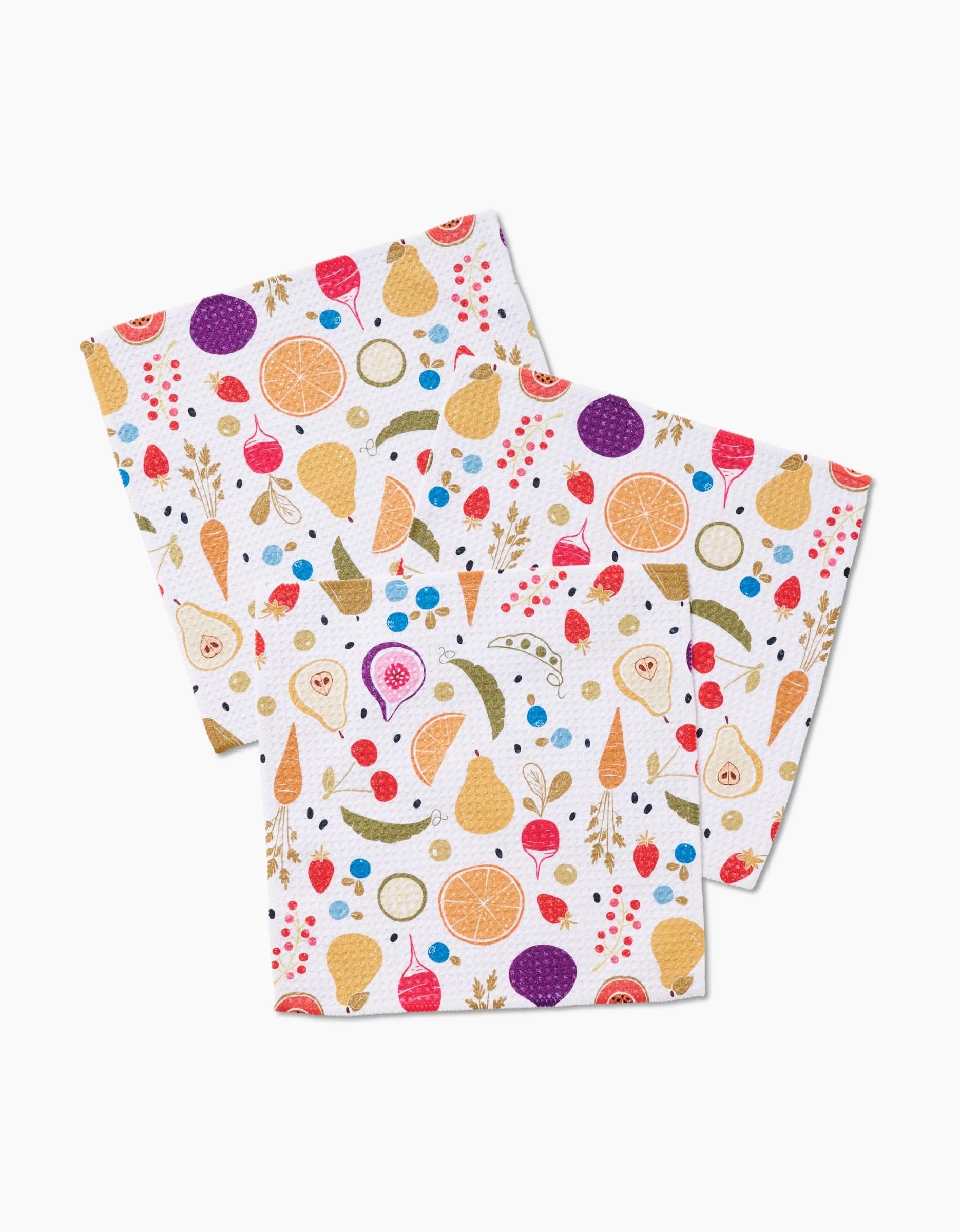 The Sara Mari Farmers Market set includes three white reusable dishcloths made from eco-friendly Geoweave fabric, featuring a vibrant fruit and vegetable pattern to brighten your kitchen.