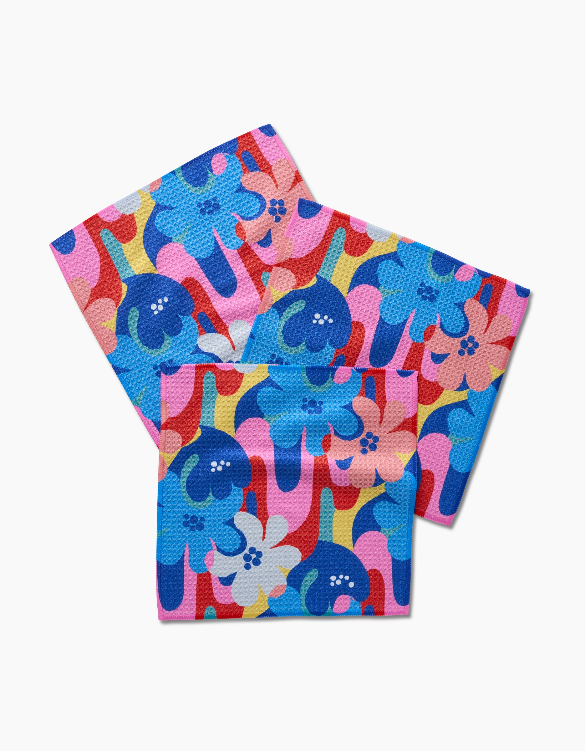 The Masha Volnova Flower Powers set includes three Geoweave dishcloths with a vibrant abstract floral pattern in blue, red, pink, and yellow on a white background.