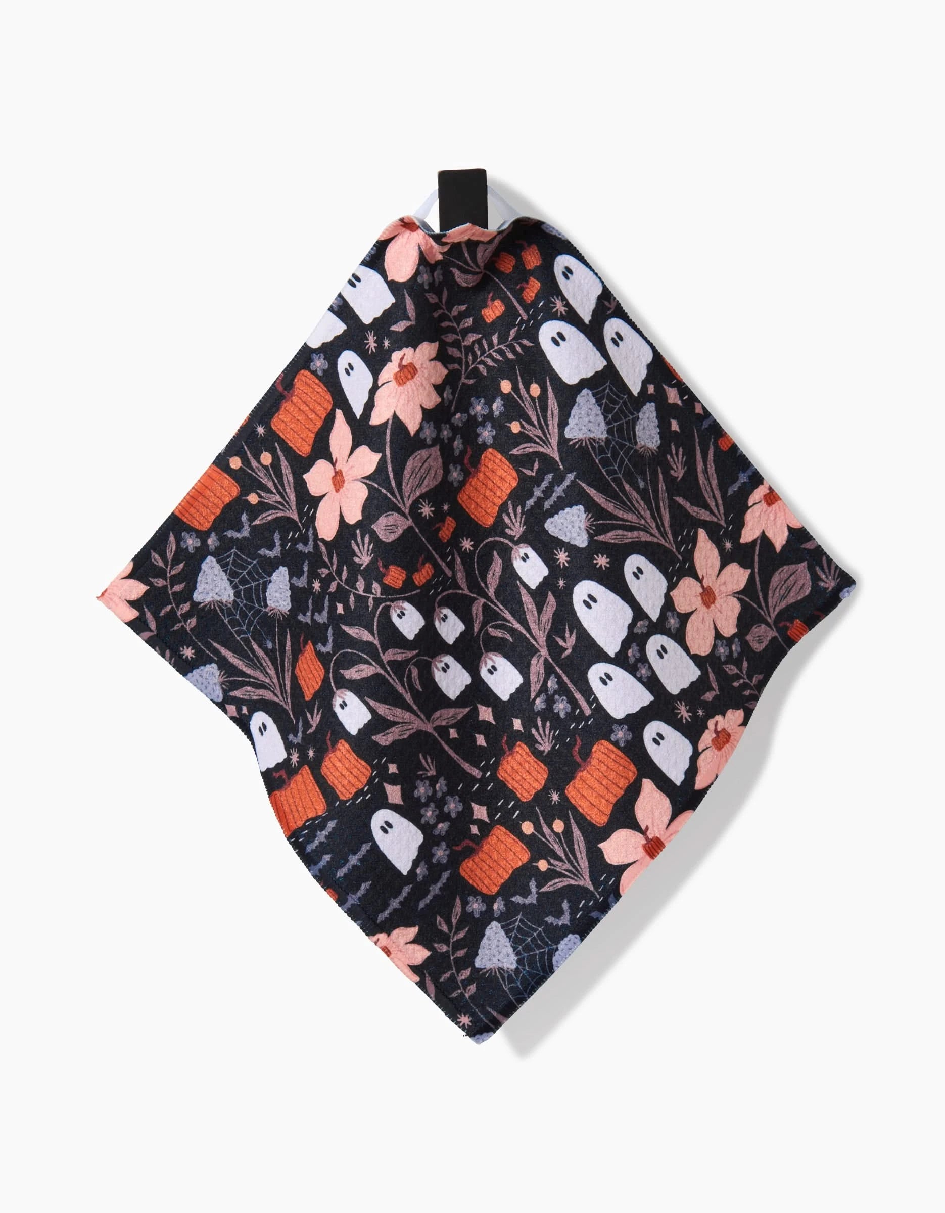The Ghosts In The Midnight Garden napkin by Charlie Rowan Designs features white ghosts, orange pumpkins, pink flowers, and blue leaves on black cloth—crafted from recycled materials for an eco-friendly touch.