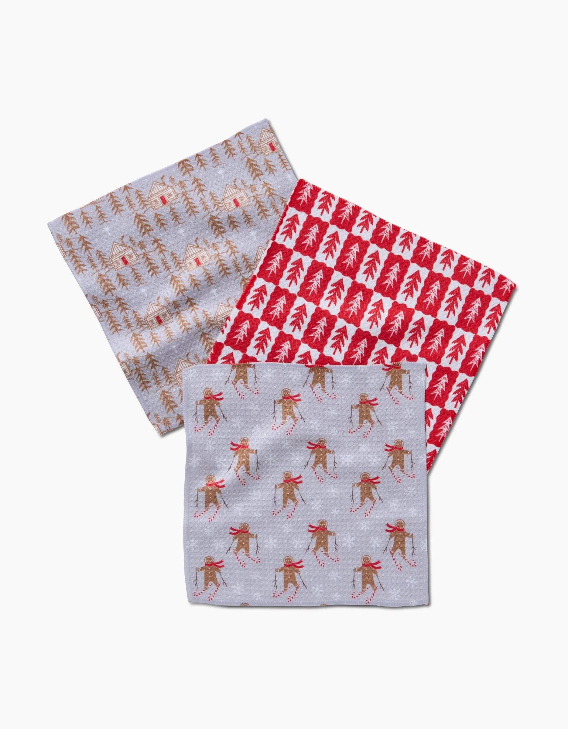 The Gingerbread Homestead dishcloths by Roxy Marj feature festive Geoweave fabric patterns: brown trees with red accents on gray, red and white Christmas trees, and reindeer skiing—perfect for brightening up your kitchen.