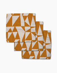 Three folded Golden Angles super-absorbent kitchen dishcloths by Lisa Nelson, featuring an orange and white geometric pattern of triangles and polygons, arranged in a staggered stack on a white background.