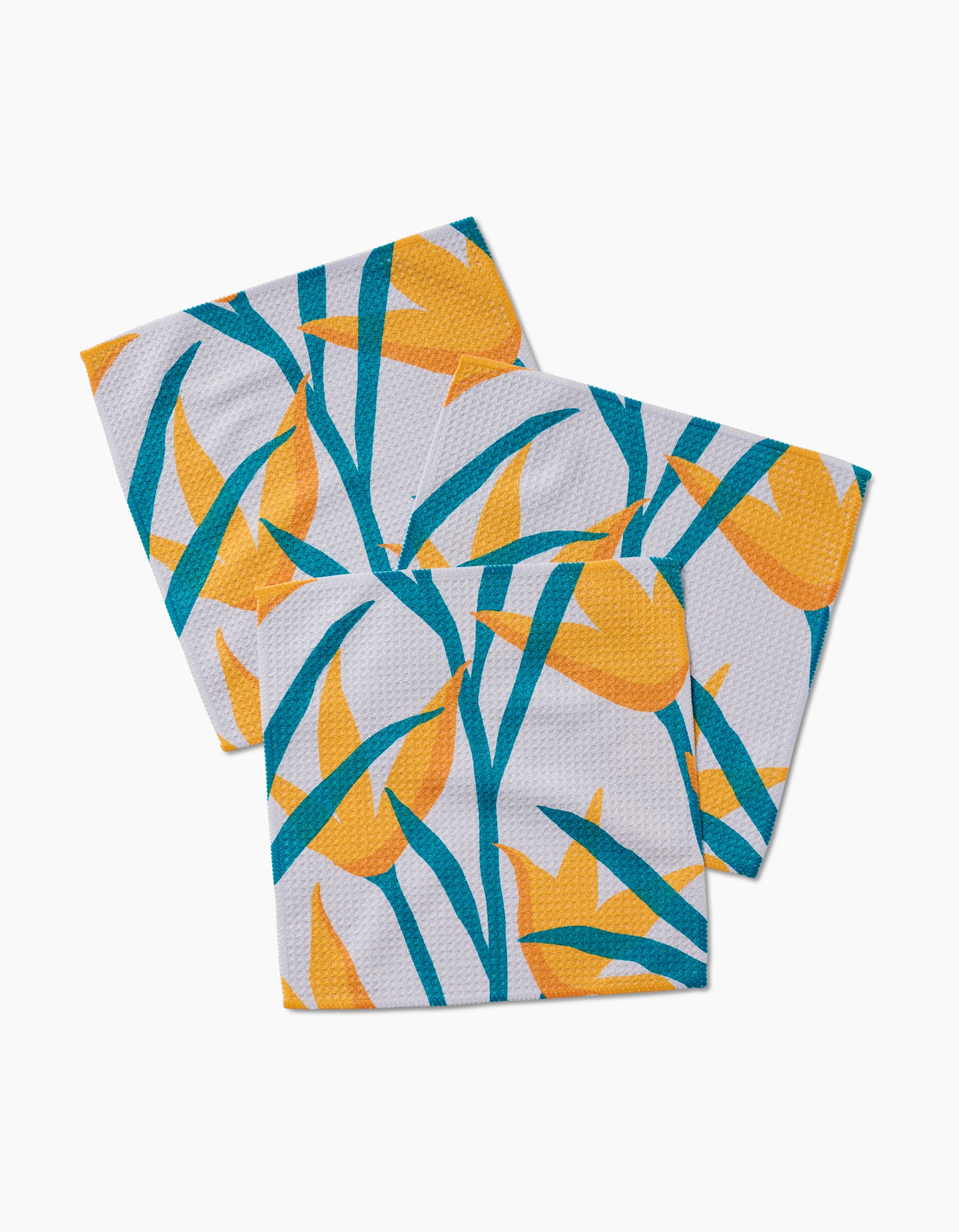 Three square GEOMETRY Geoweave napkins from the Growth collection, featuring a colorful pattern of yellow flowers and green leaves on white, arranged to overlap slightly.