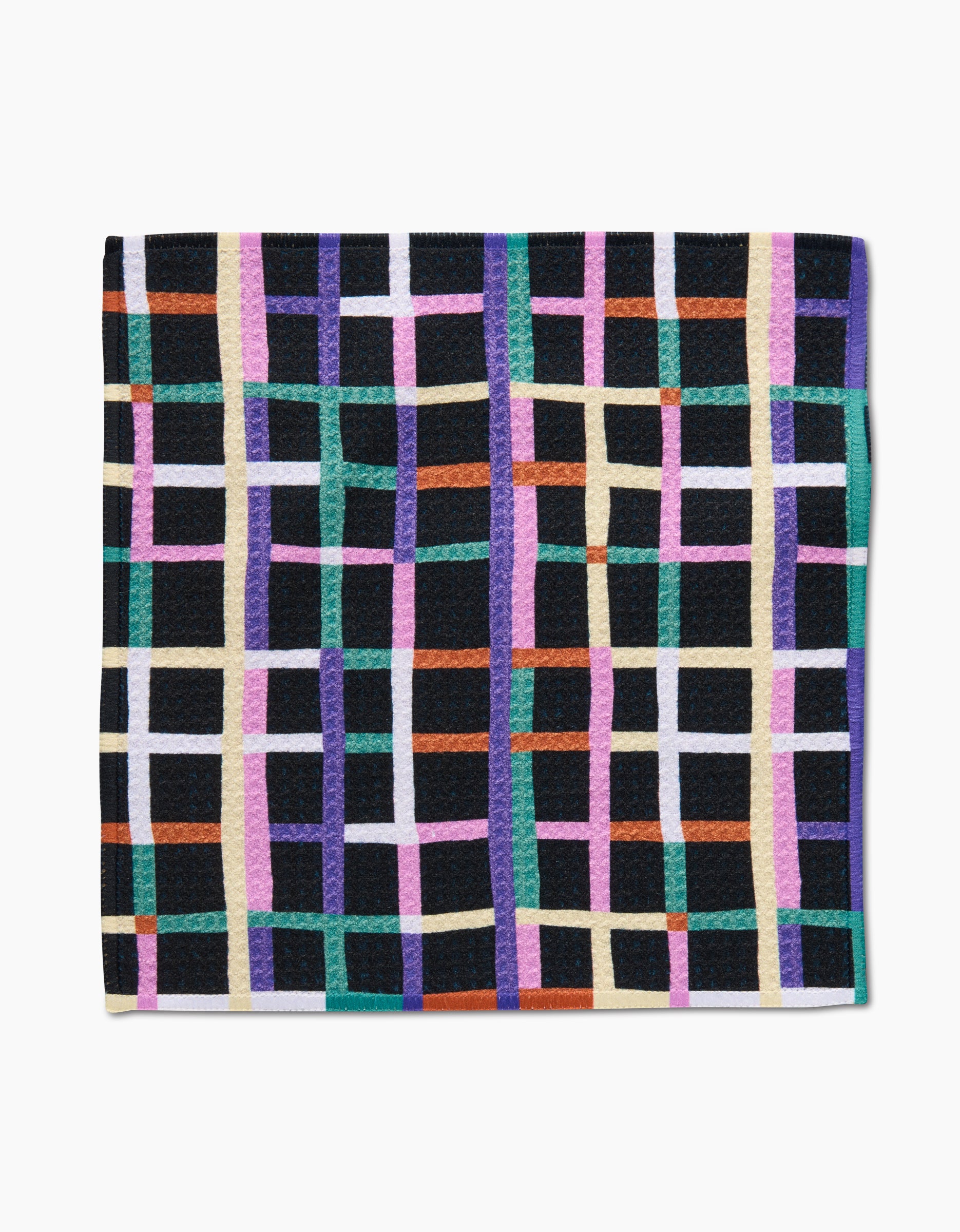 The Happy Plaid dishcloth by Claire Iglesias features a square shape and Geoweave fabric, showcasing a vibrant grid of green, purple, orange, white, and yellow stripes on black for a stylish and functional look.