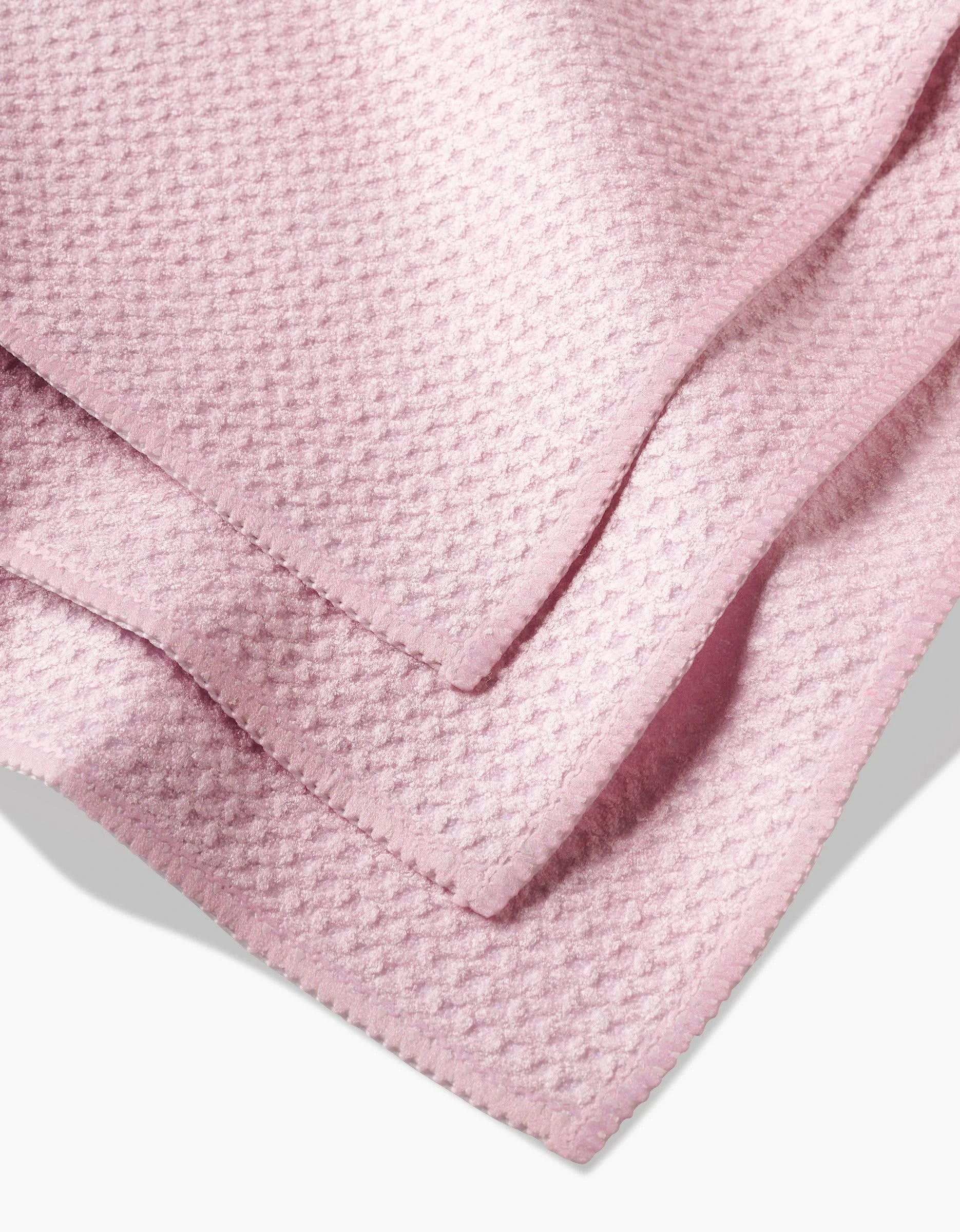 A close-up of Harper Pink Geoweave fabric, soft and light pink with small raised patterns and zigzag-cut edges—perfect for a high-performing dishcloth set.