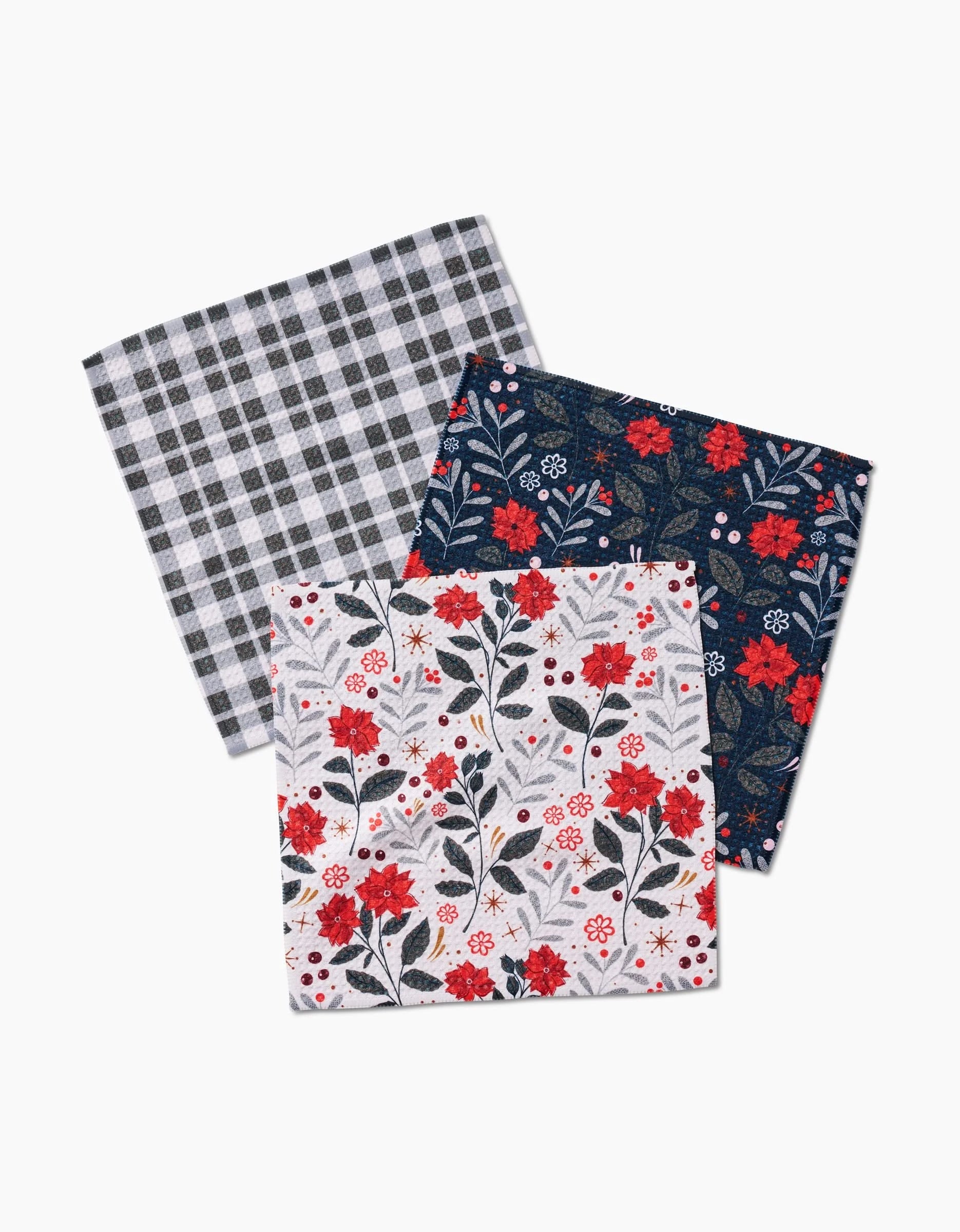 Three super-absorbent handkerchiefs from Charlie Rowan Designs’ Holiday Floral set—featuring black & white plaid, dark blue with red & white florals, and white with red & black florals—overlap in a stylish arrangement.