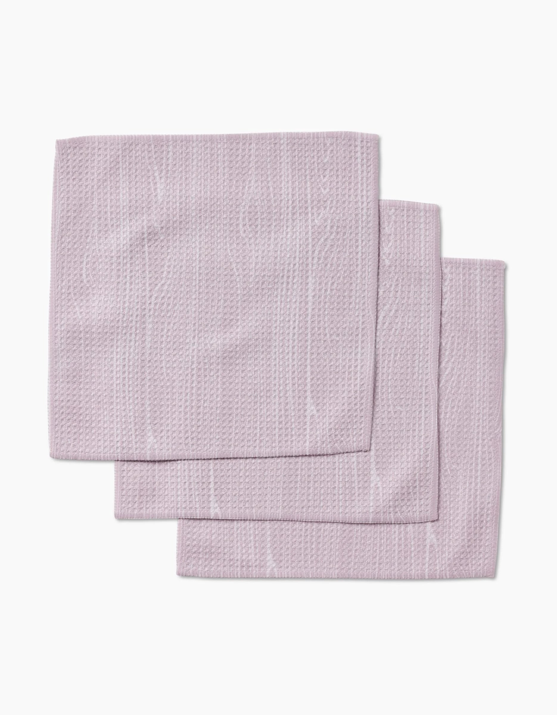 Three folded, textured, light purple Houston Wood dishcloth napkins by Kailee Wright, made from Geoweave fabric, are neatly stacked on a plain white background.