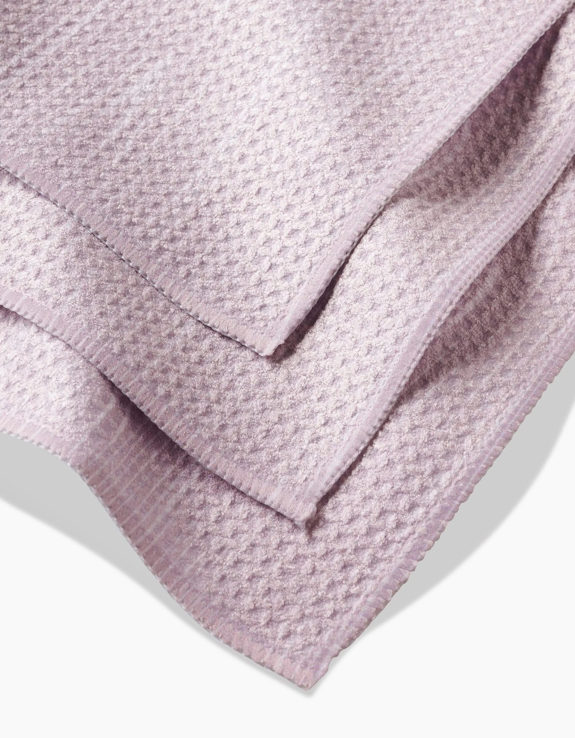 A close-up view of folded Houston Wood dishcloth by Kailee Wright features textured, waffle-like Geoweave fabric in light lavender with neatly finished edges.
