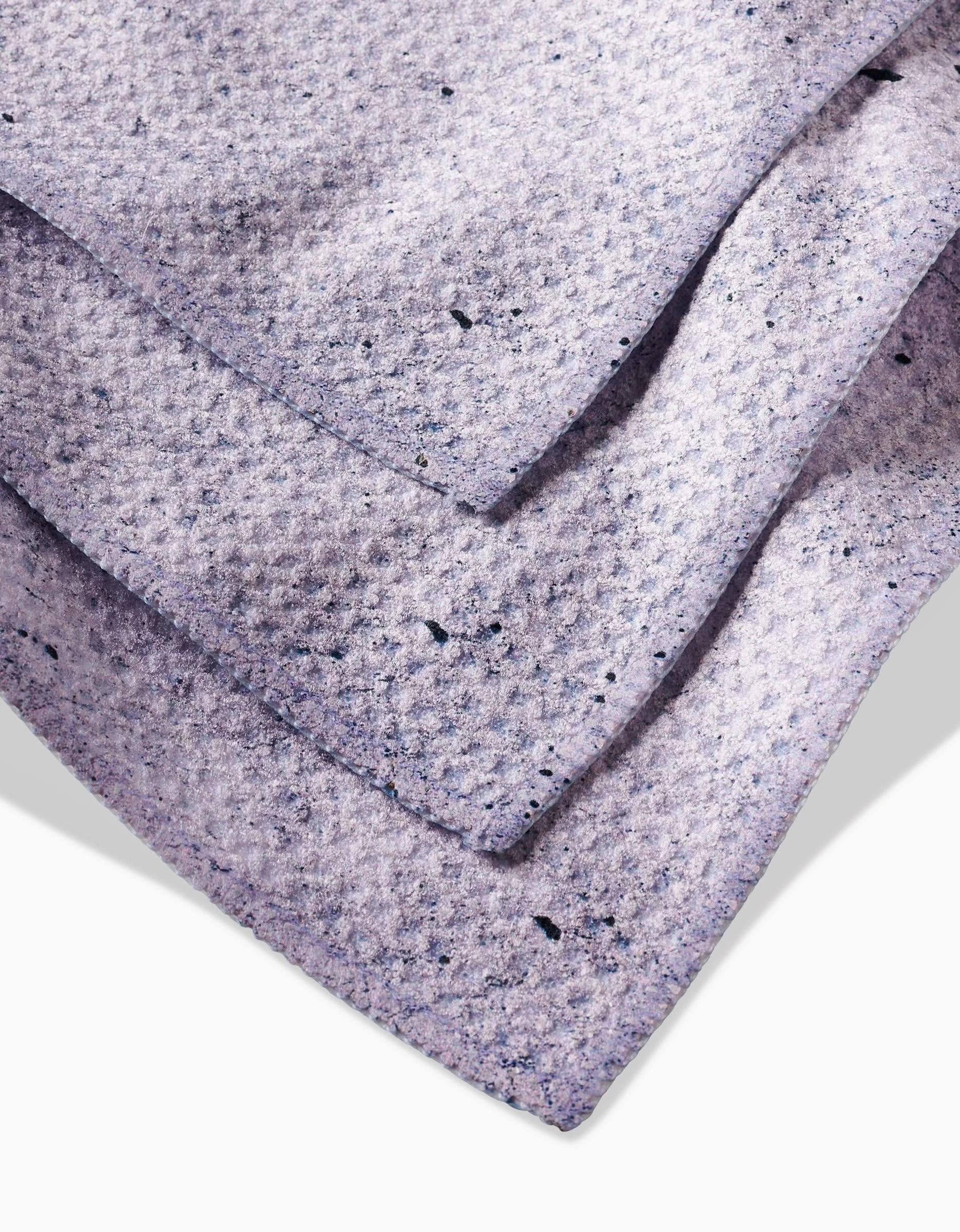 Close-up view of three overlapping Hudson Grey dishcloths by Kailee Wright, featuring Geoweave fabric with dark speckles, arranged on a white surface.