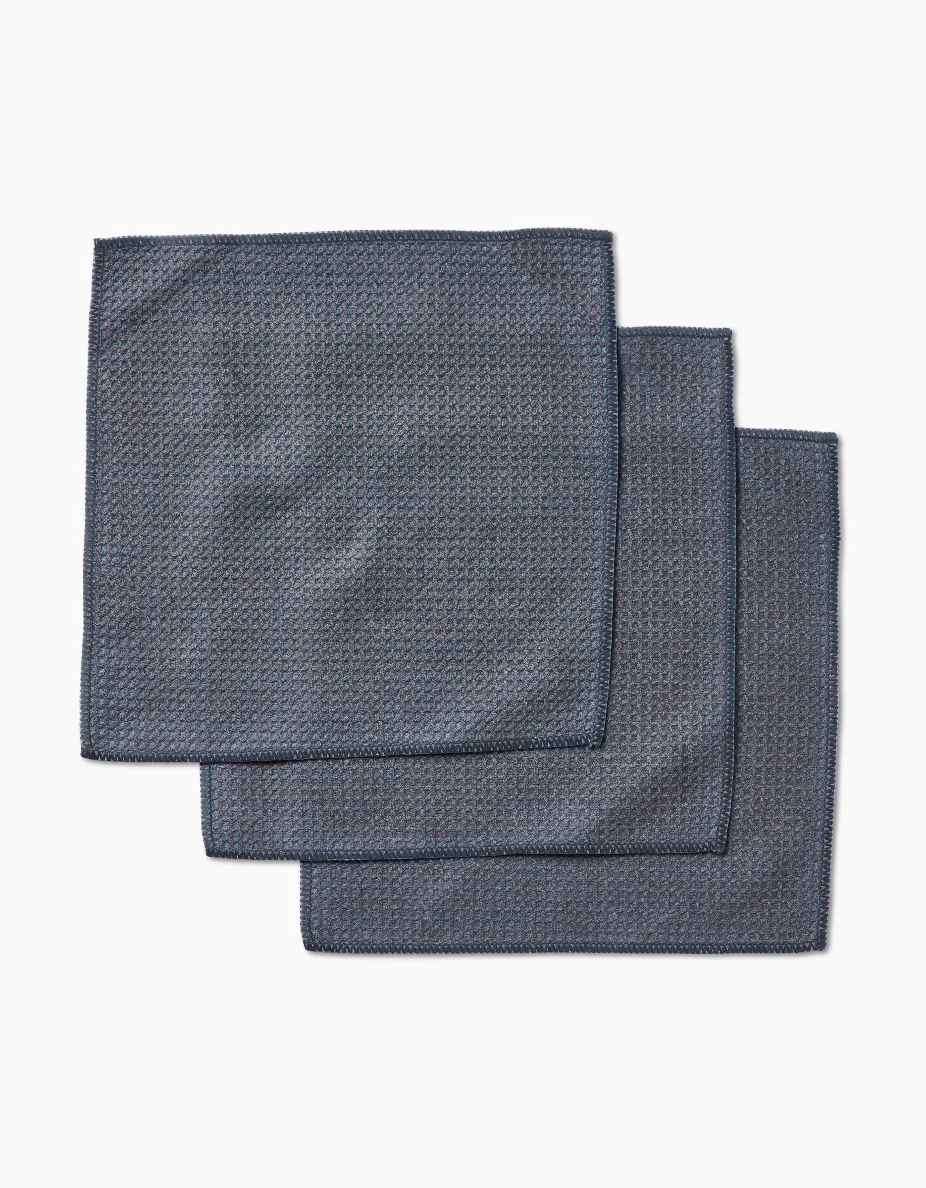 Three neatly stacked hunter green cloth napkins by Kailee Wright, crafted from super-absorbent Geoweave fabric, rest on a white background.