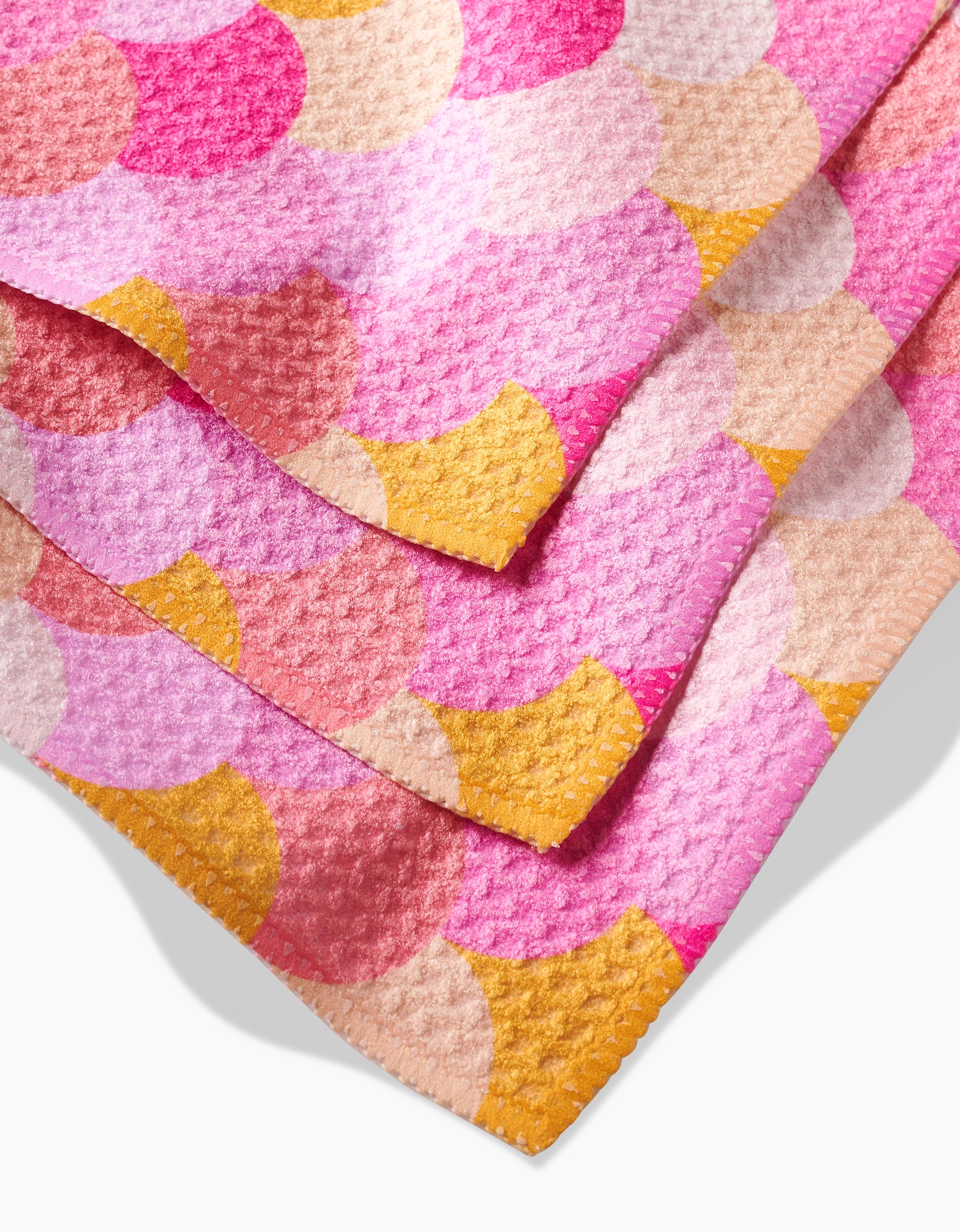 Three Inherit dishcloths by GEOMETRY feature a pink and yellow scallop pattern, stacked to show their soft Geoweave fabric. Durable and colorful, this set brightens your kitchen while offering lasting quality.