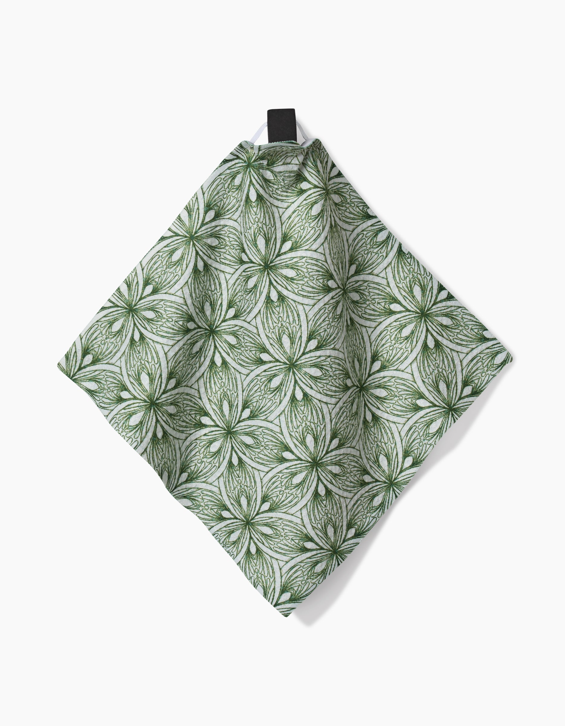 The Interlaced Petals dishcloth by Marta Harvey features a green and white floral pattern with symmetrical, overlapping petals. Made from recycled materials, it has a black hanging loop and is shown against a white background.