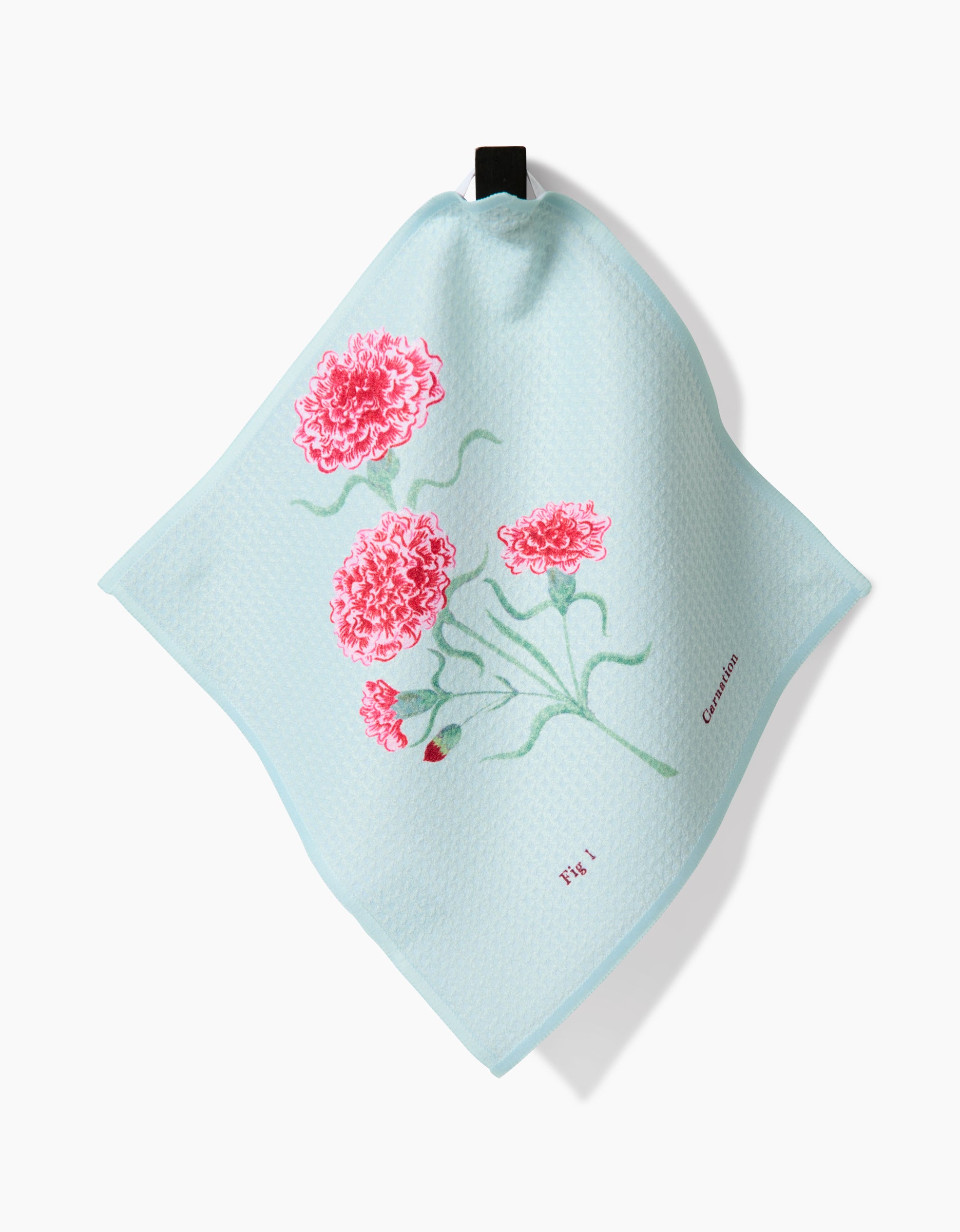 The January Carnation dishcloth by Linda Fox features light blue Geoweave fabric, embroidered pink carnations with green stems, “Carnation” and “TY 4” stitched in small letters, and a black hanging loop—perfect for a stylish dishcloth set.