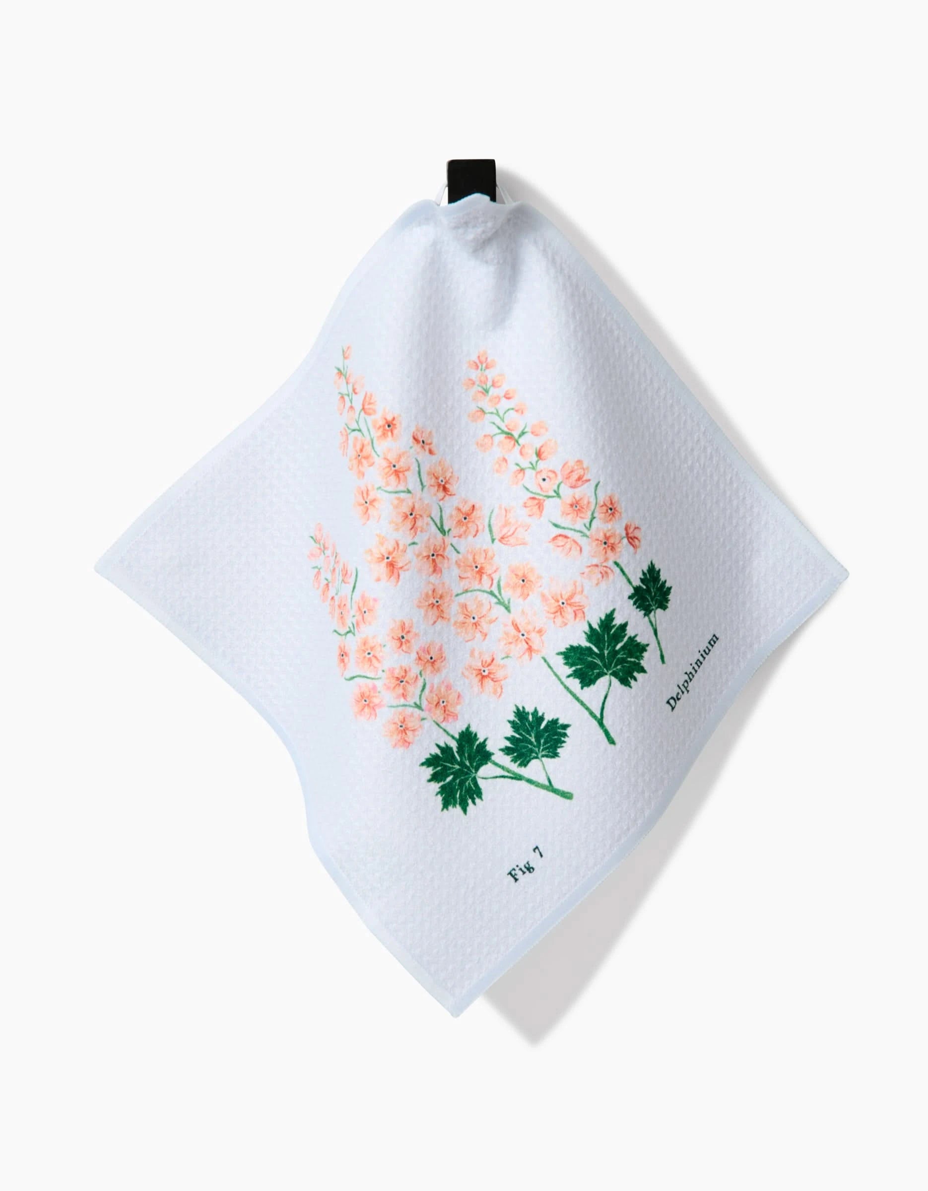 The Linda Fox July Delphinium dishcloth is white and textured, made from recycled materials, with pink and green botanical artwork labeled Delphinium and Fig 7, and features a black hanging loop.