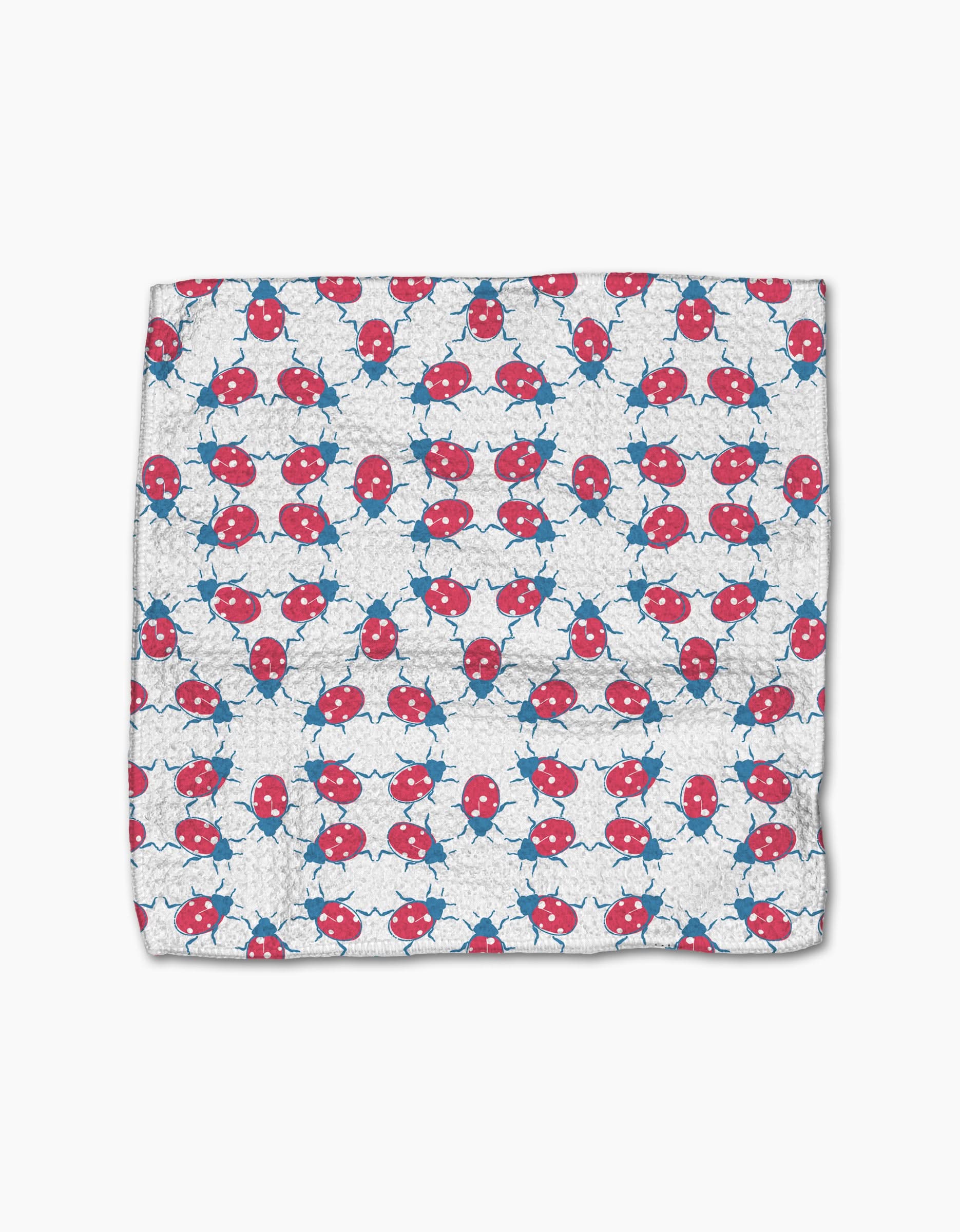 The Ladybug Dance dishcloth by Second Nature Studio features a white Geoweave fabric with rows of playful red and blue ladybugs, crafted from recycled materials for an eco-friendly touch.