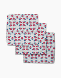 Three white dishcloth napkins from Second Nature Studio’s Ladybug Dance, made with Geoweave fabric and featuring a playful pattern of red and blue ladybugs and blue geometric stars, are shown slightly overlapping on a white background.