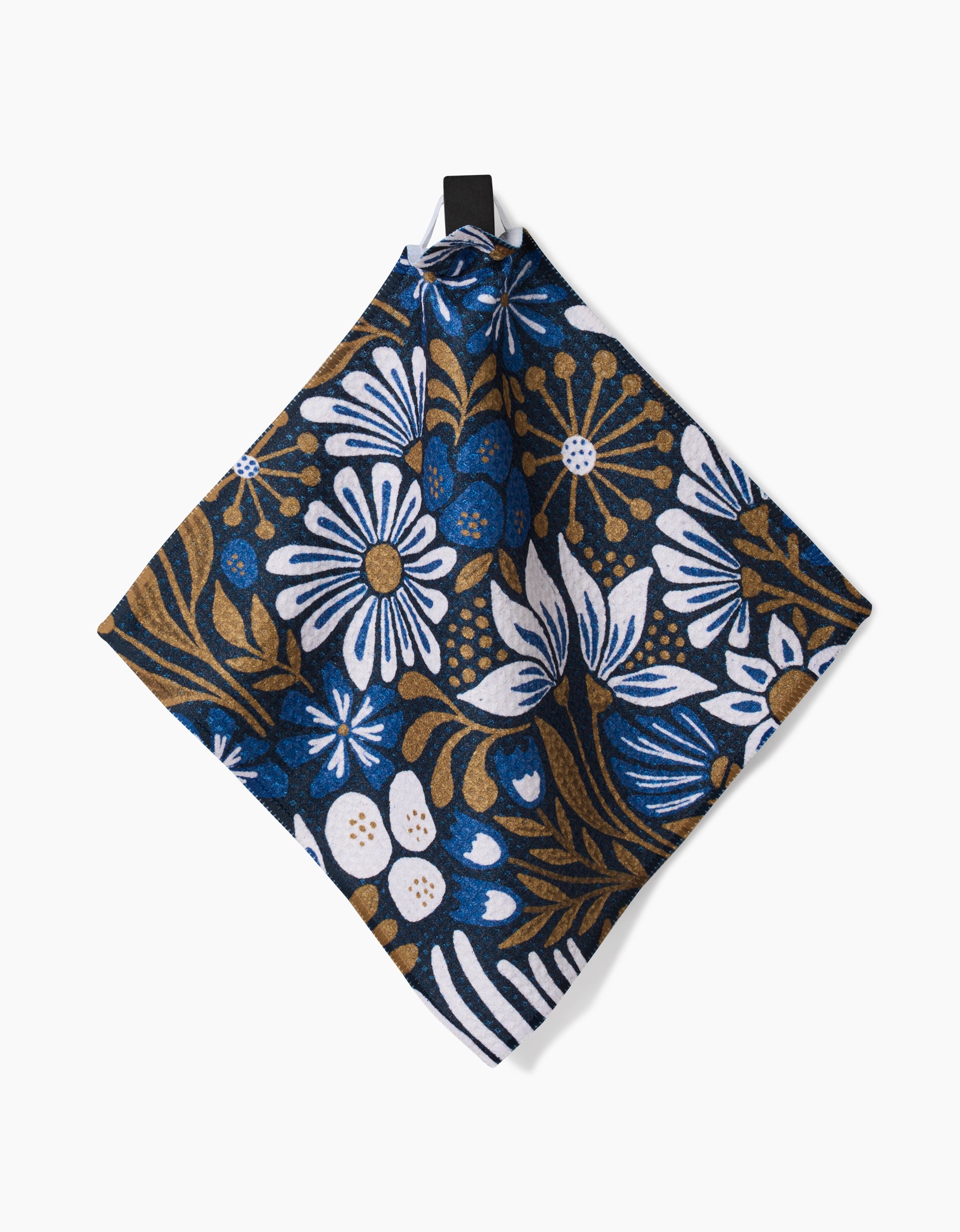 The Leslie Flowers napkin by Amy MacCready features a bold white, blue, and brown floral pattern on dark fabric. Made from super-absorbent recycled materials, it’s ideal as a dishcloth or table accent and includes a handy loop for hanging.