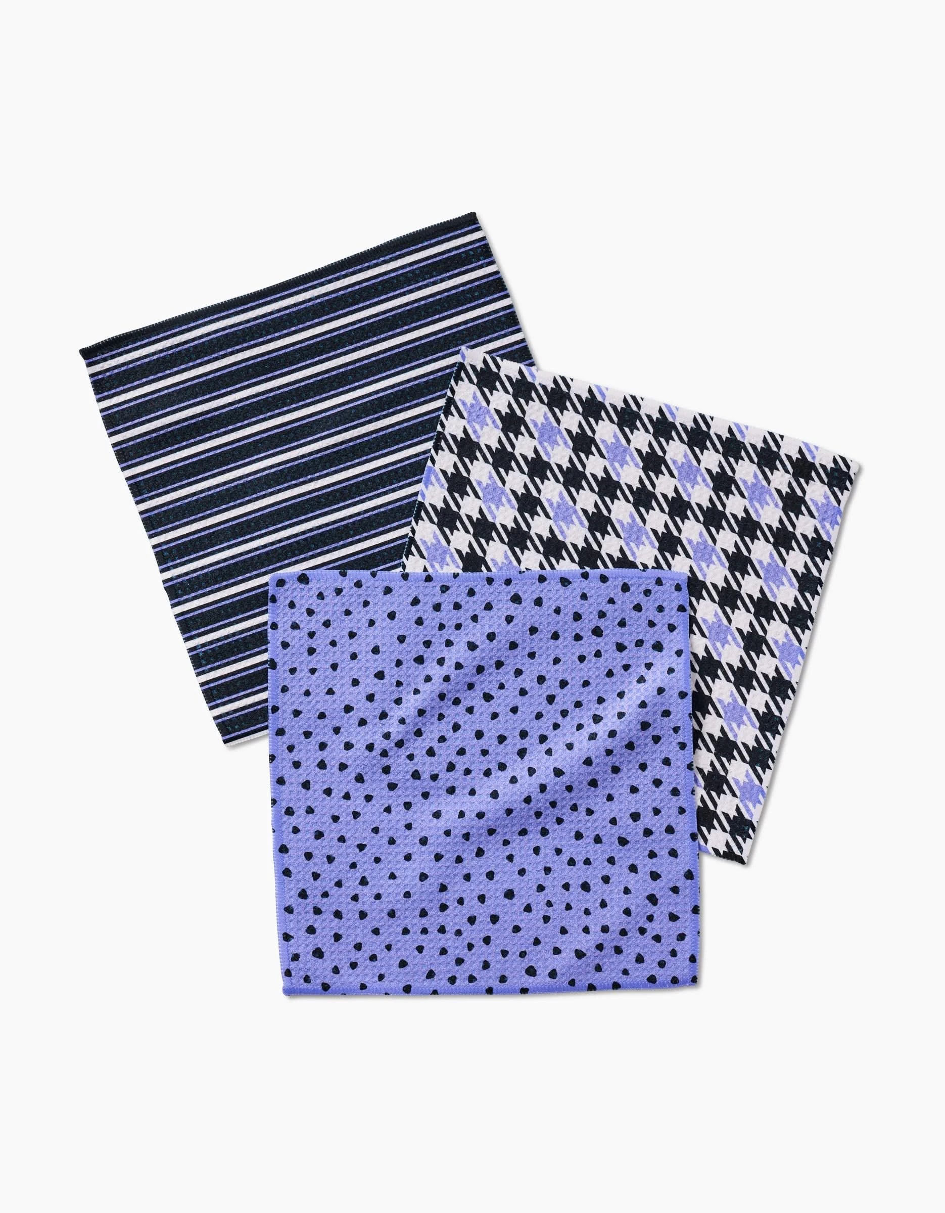 Three “Lilac Schemes” handkerchiefs by Hufton Studio, crafted from recycled materials, overlap: one with navy and white stripes, one with a black and white diamond pattern, and one with black dots on a light blue background.