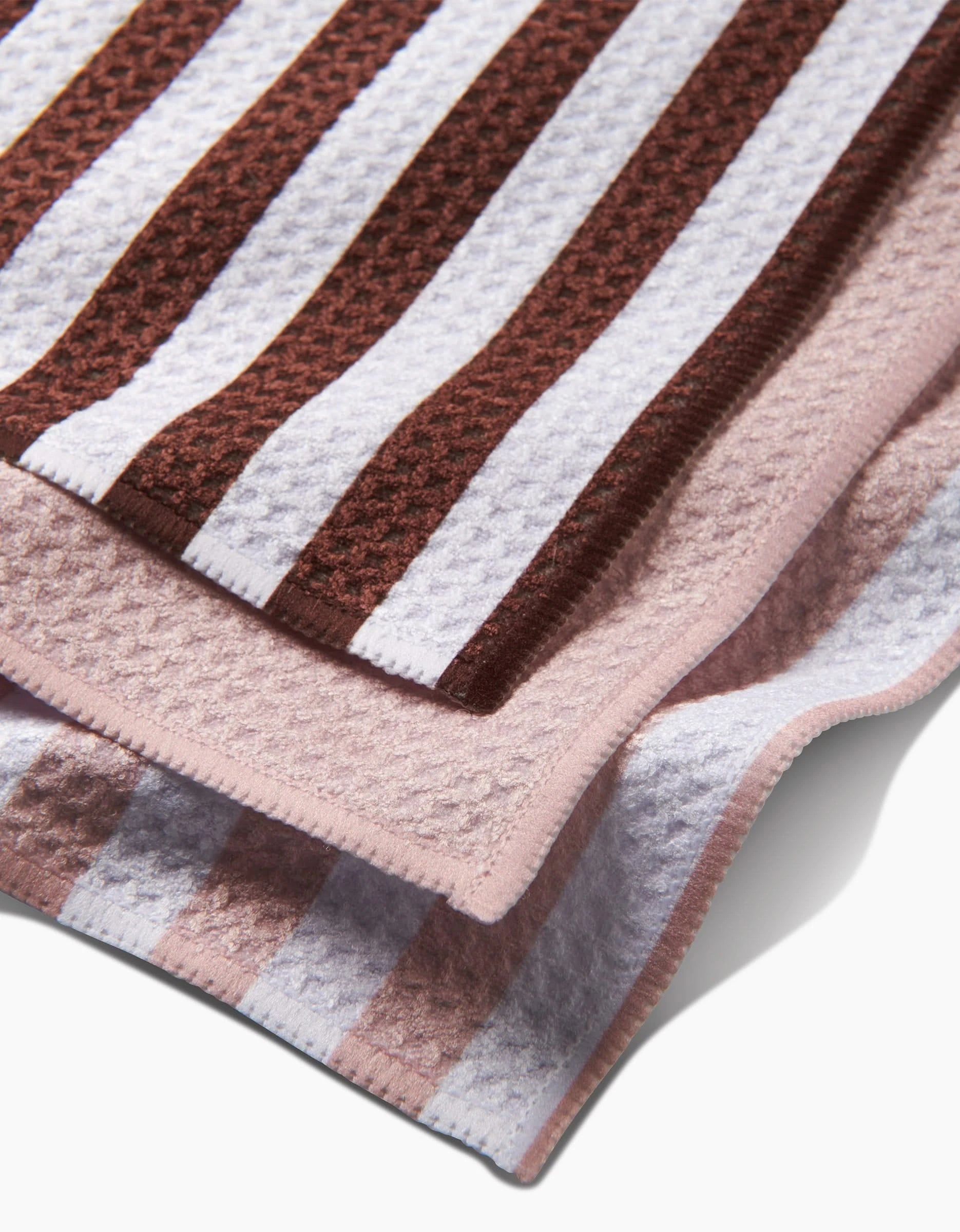 Close-up of the Mama Dishcloth Set by Kailee Wright, featuring two Geoweave towels with textured wide stripes—one brown and white, the other pink and white—layered to highlight their unique patterns and finished edges.