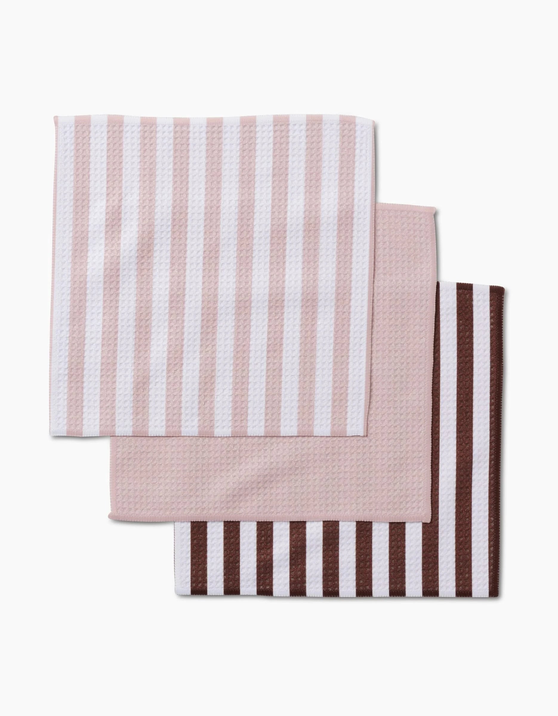 Three folded Kailee Wright Mama cloths stacked: the top has light pink and white vertical stripes, the middle is solid light pink, and the bottom features dark brown and light pink stripes—all made from durable Geoweave fabric.