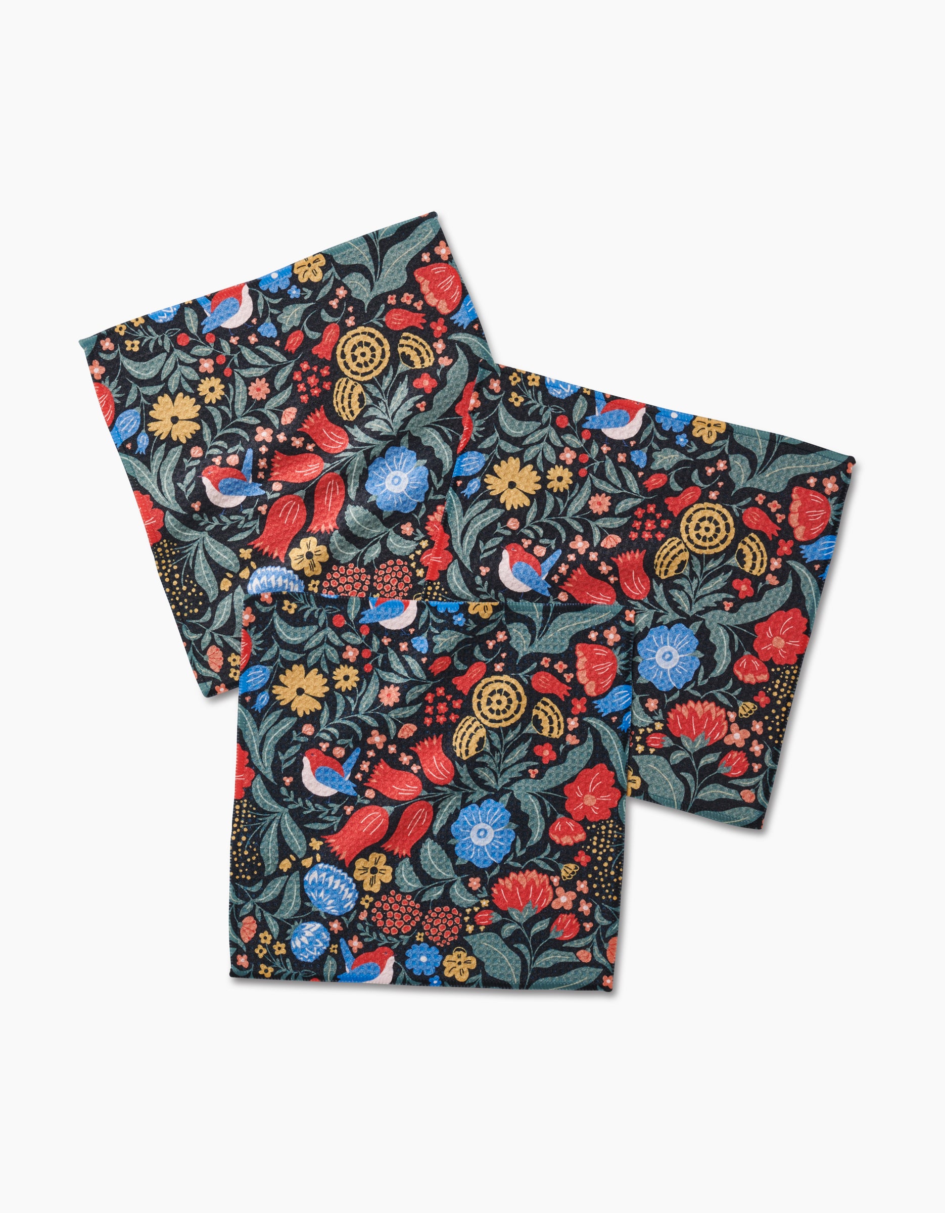 Two square Marsh Wren napkins by Danelys Sidron, featuring overlapping corners and a colorful floral and bird pattern with red, blue, and yellow flowers, green leaves, and small birds on a black background.
