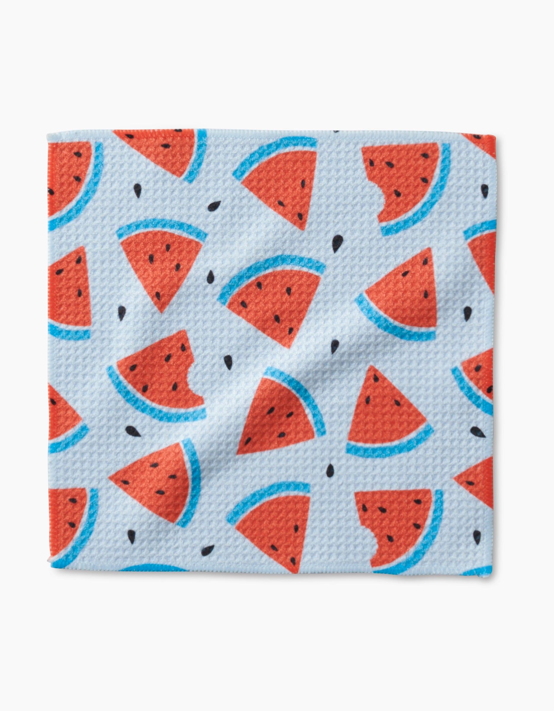 The Sara Mari Melon Mingle dishcloth features textured blue Geoweave fabric with a playful pattern of red watermelon slices—some bitten—plus black seeds for a fresh, summery touch.