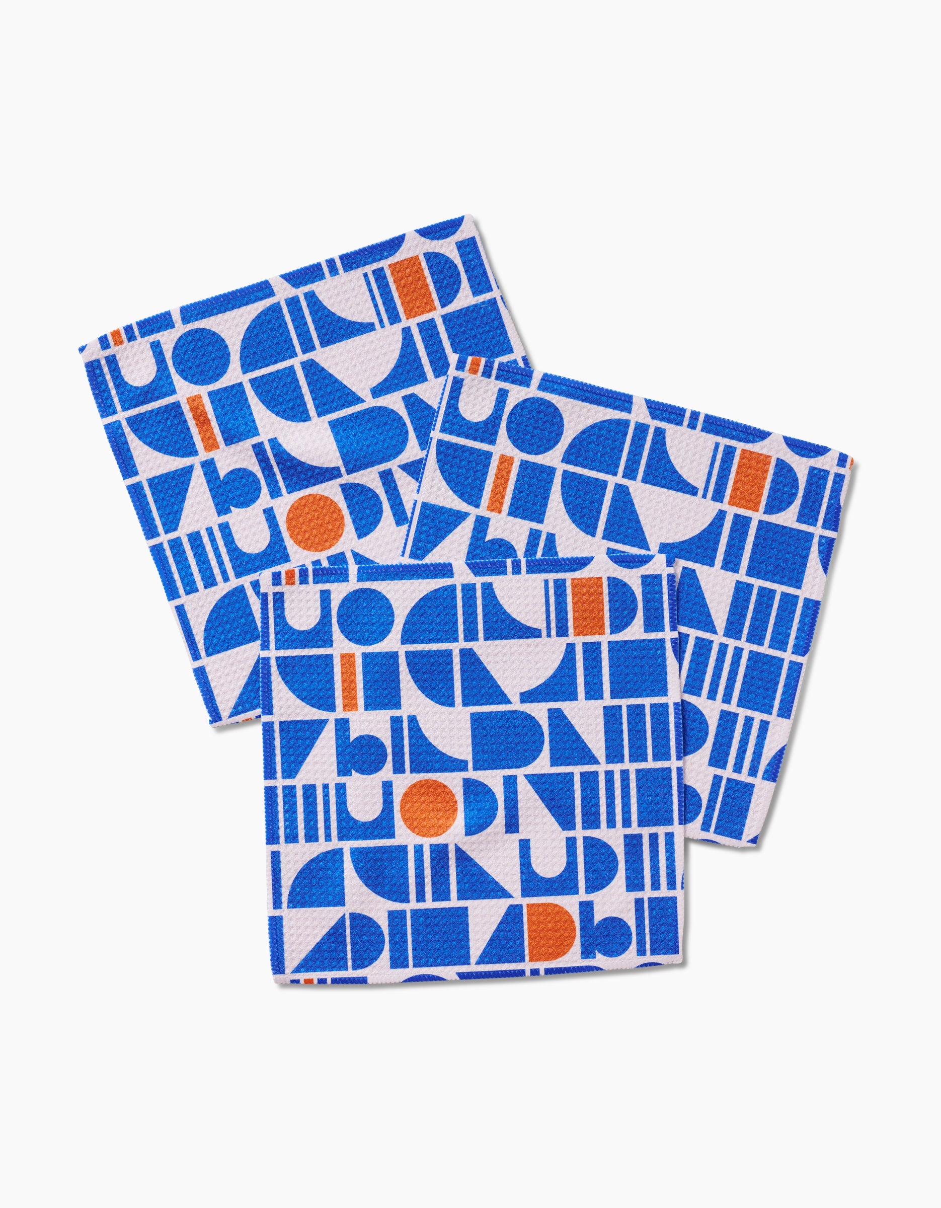 Three Misty Oasis square coasters by Happy Hemera, in blue, orange, and white with bold geometric shapes, crafted from recycled materials, are slightly overlapping each other on a white background.