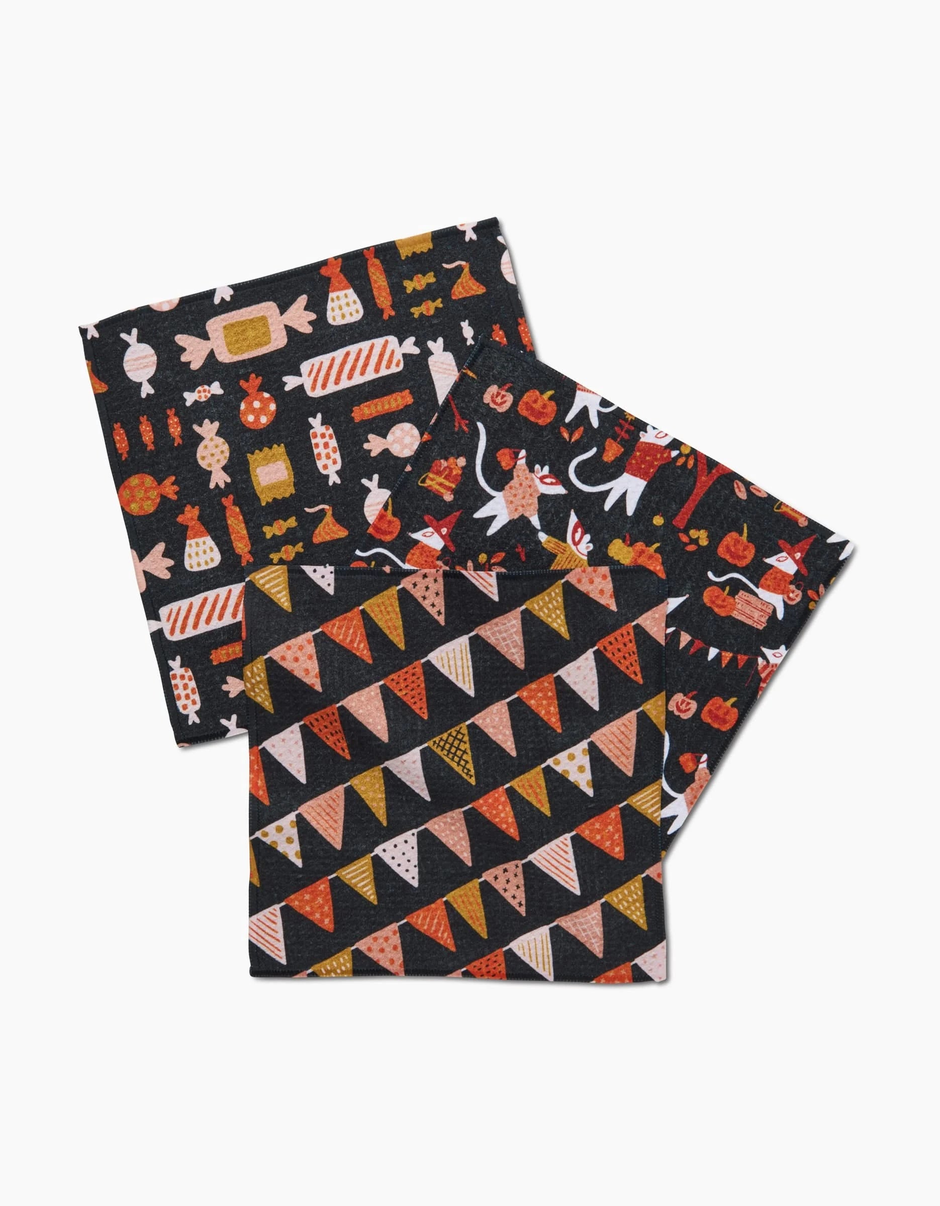 Morticia Edwina And Morrigan by Amy MacCready: two recycled square cloths—one with orange, black, and white bunting flags; the other with assorted candies, pumpkins, and autumn motifs on a black background.