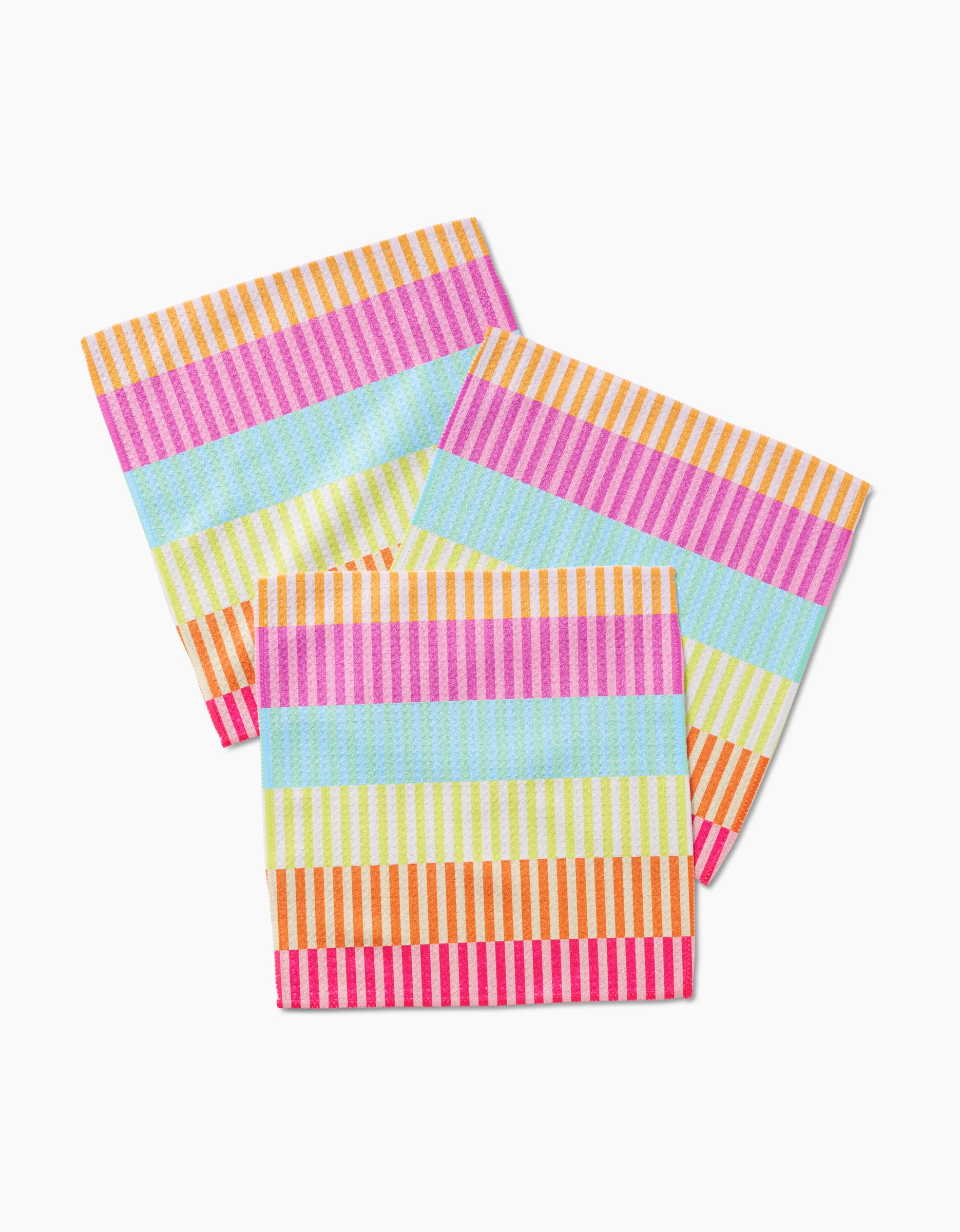 The Neon Nights set by GEOMETRY includes three square Geoweave napkins with colorful overlapping horizontal stripes—pink, orange, yellow, green, and blue—on a white background.
