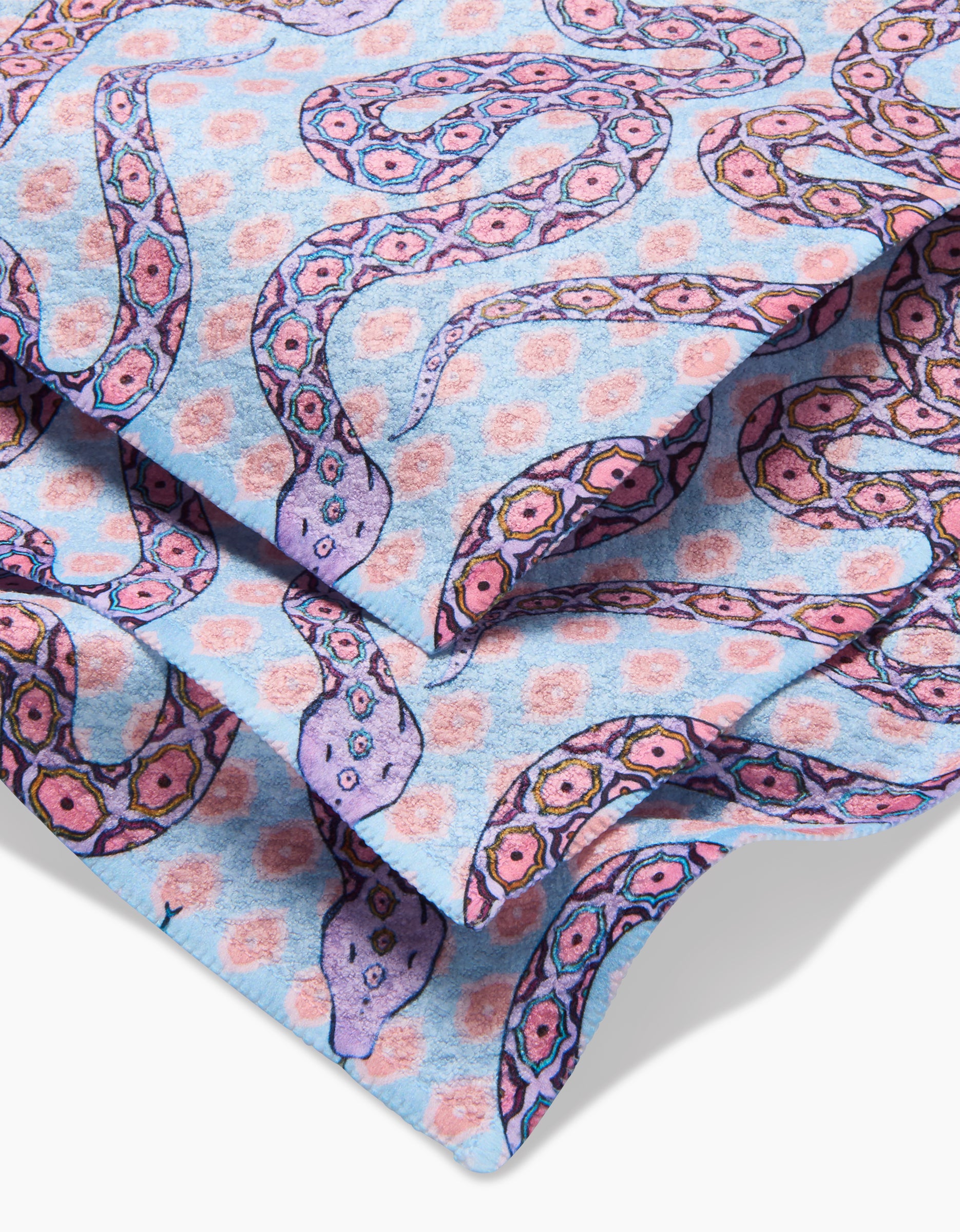 A close-up of Ophidia, a Geoweave dishcloth by Maayan Alper-Swan, made from recycled materials and featuring pink and purple snakes with pink dots on a light blue background.