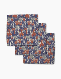 Geometry’s Parading Cats features three folded recycled cloth napkins with a playful design of illustrated cats in blue, red, and cream on a dark background. Their charming poses add whimsy to these eco-friendly dishcloths.