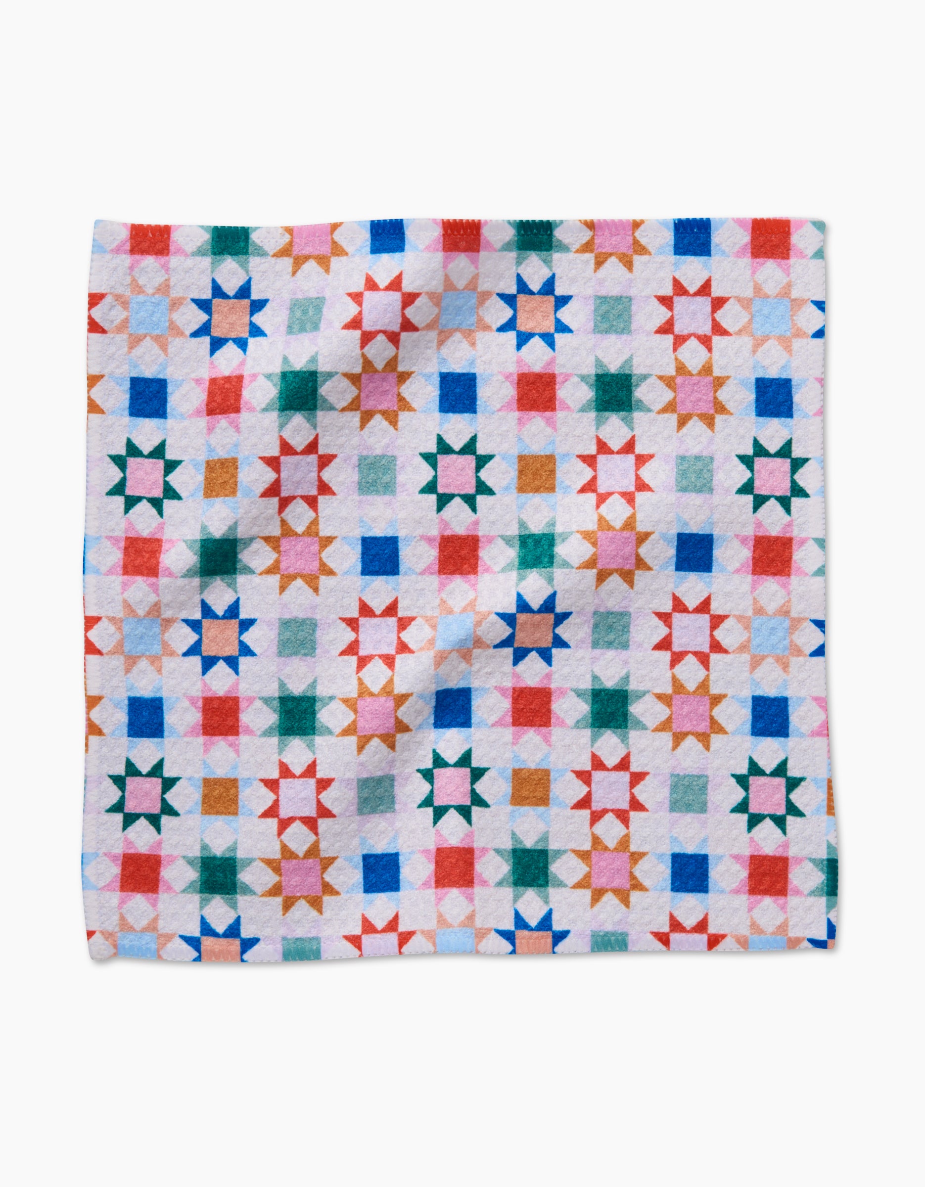 Patchwork Picnic by Brittany Jepsen is a vibrant dishcloth made from recycled materials, featuring a quilt-inspired geometric star pattern in red, blue, green, orange, and pink on white with intersecting shapes arranged in a grid.