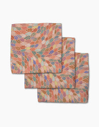 Three folded Peachy Leaf Swirl napkins from Rachel Parker, featuring a multicolored leaf pattern on peach, are stacked on white—a stylish and eco-friendly addition to any dishcloth set.