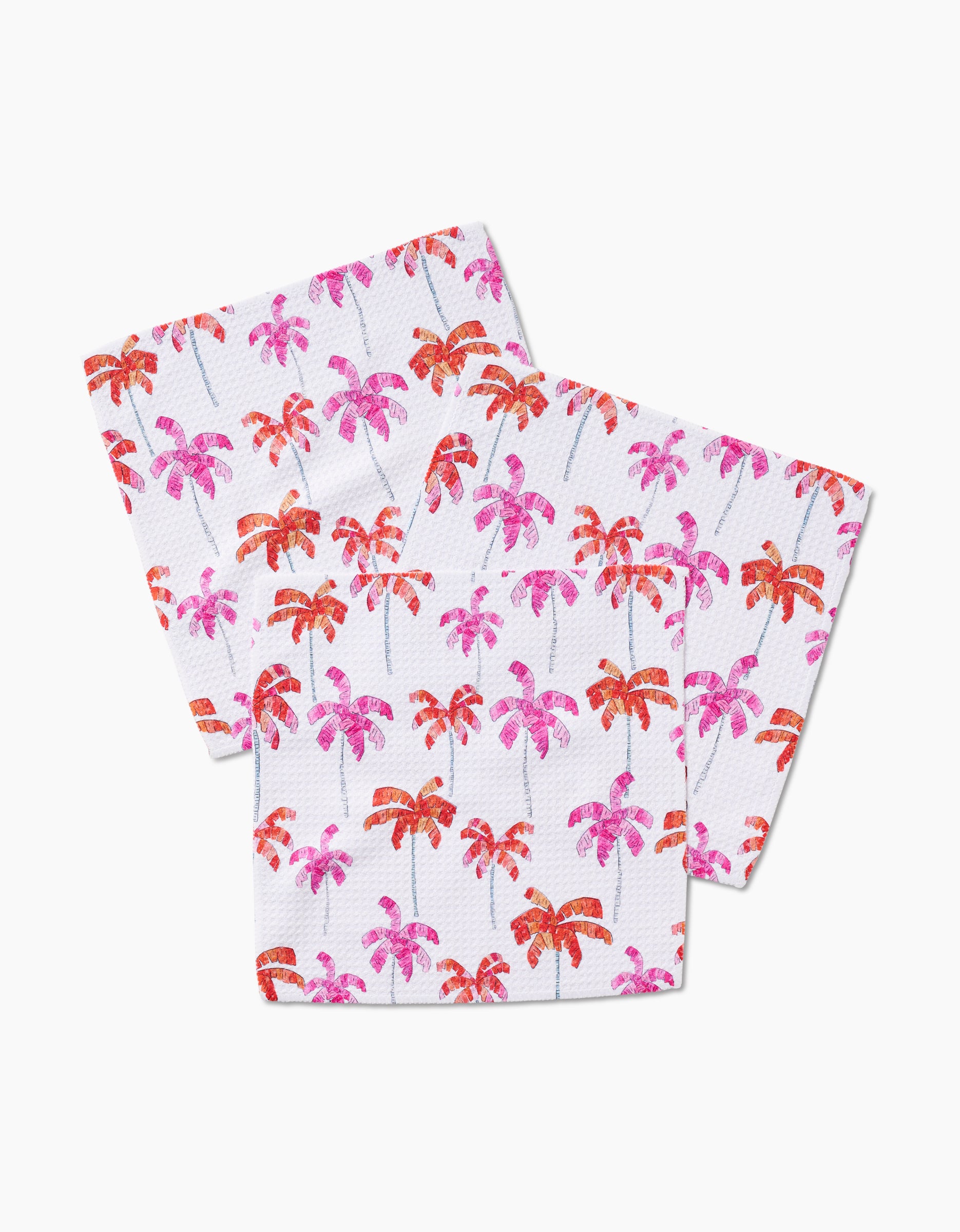 Three white paper napkins from GEOMETRY’s Pink Palms collection, featuring a vibrant pattern of pink and red palm trees inspired by lively dishcloth designs.