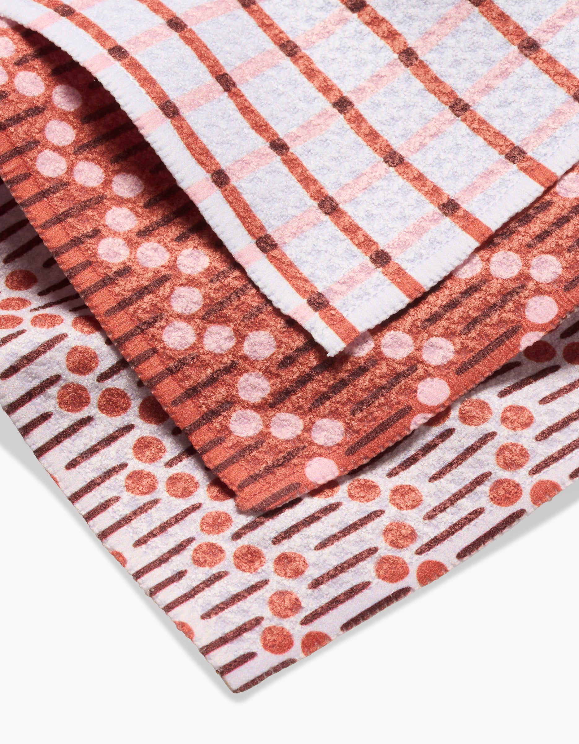The Playful Retro dishcloth set by Teri the Butter features three folded cloths in red and white plaid, pink polka dots with brown stripes, and Geoweave fabric with red dots and diagonal brown lines on white.